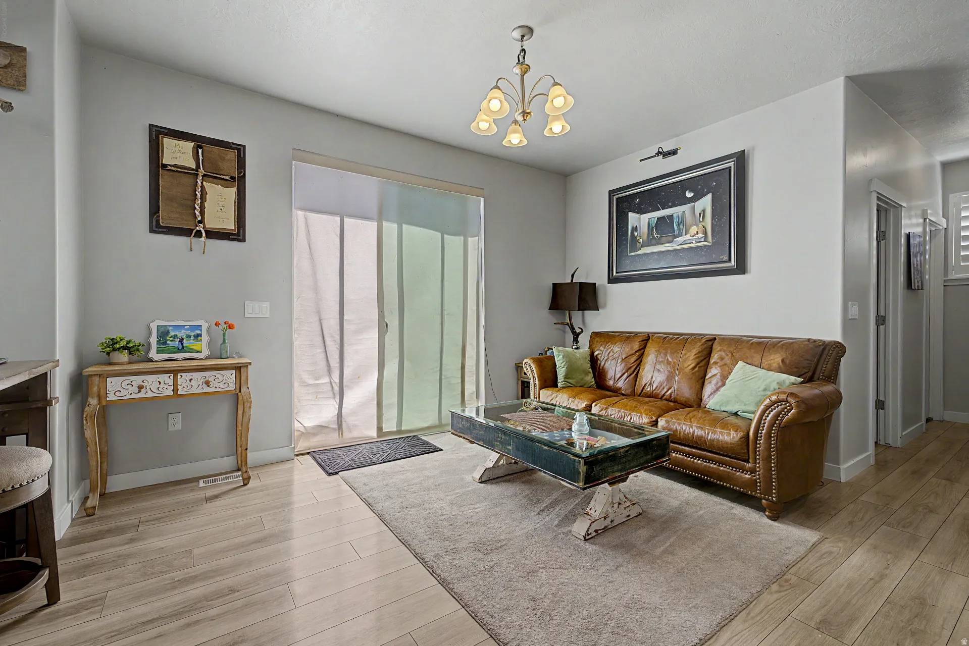 Living area with light wood-type flooring and suspended lighting