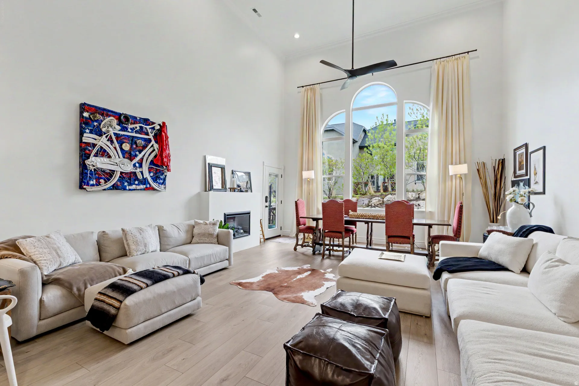Living room with a high ceiling, wood finished floors, and a glass covered fireplace