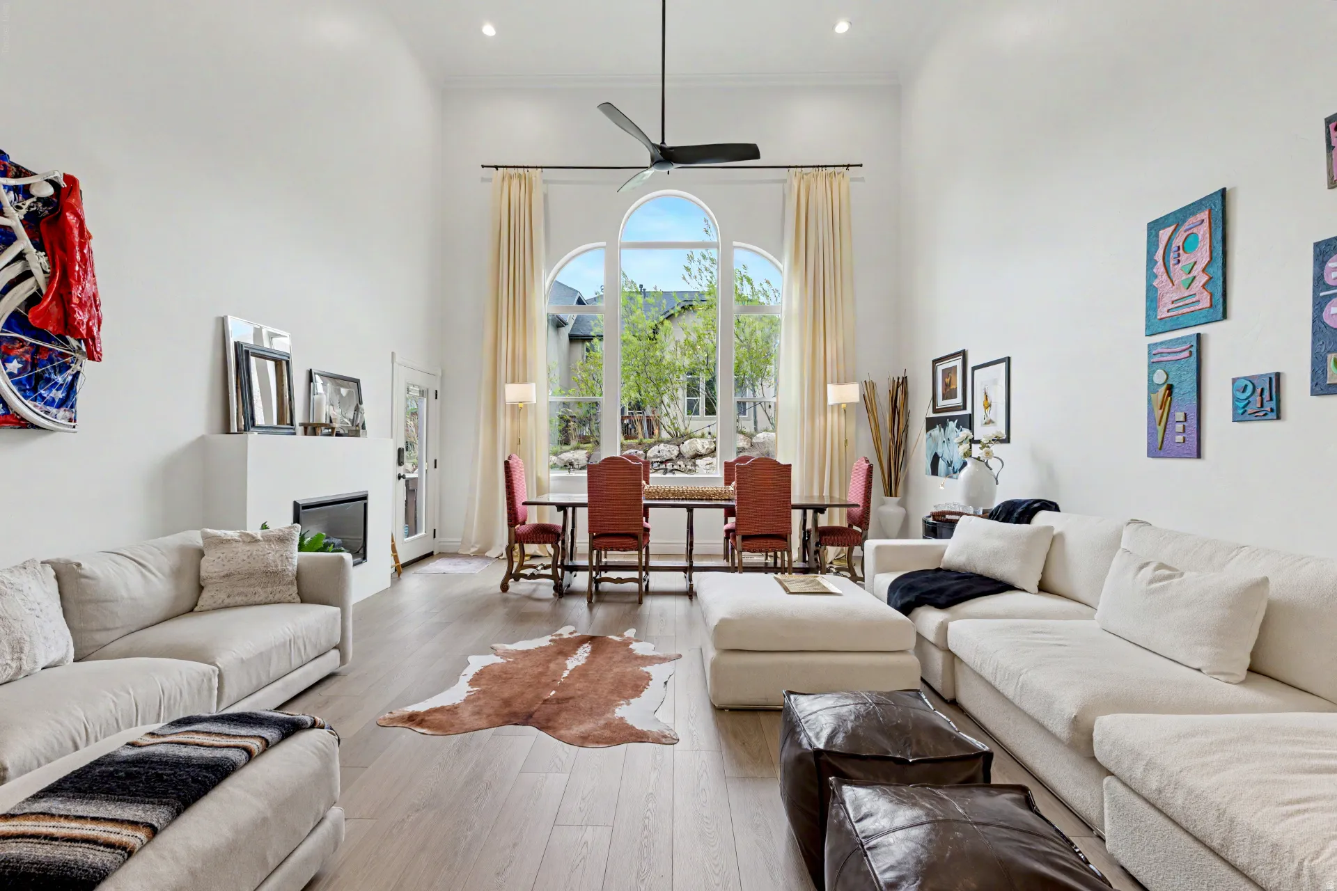 Living area featuring a high ceiling, hardwood / wood-style flooring, ceiling fan, a glass covered fireplace, and recessed lighting