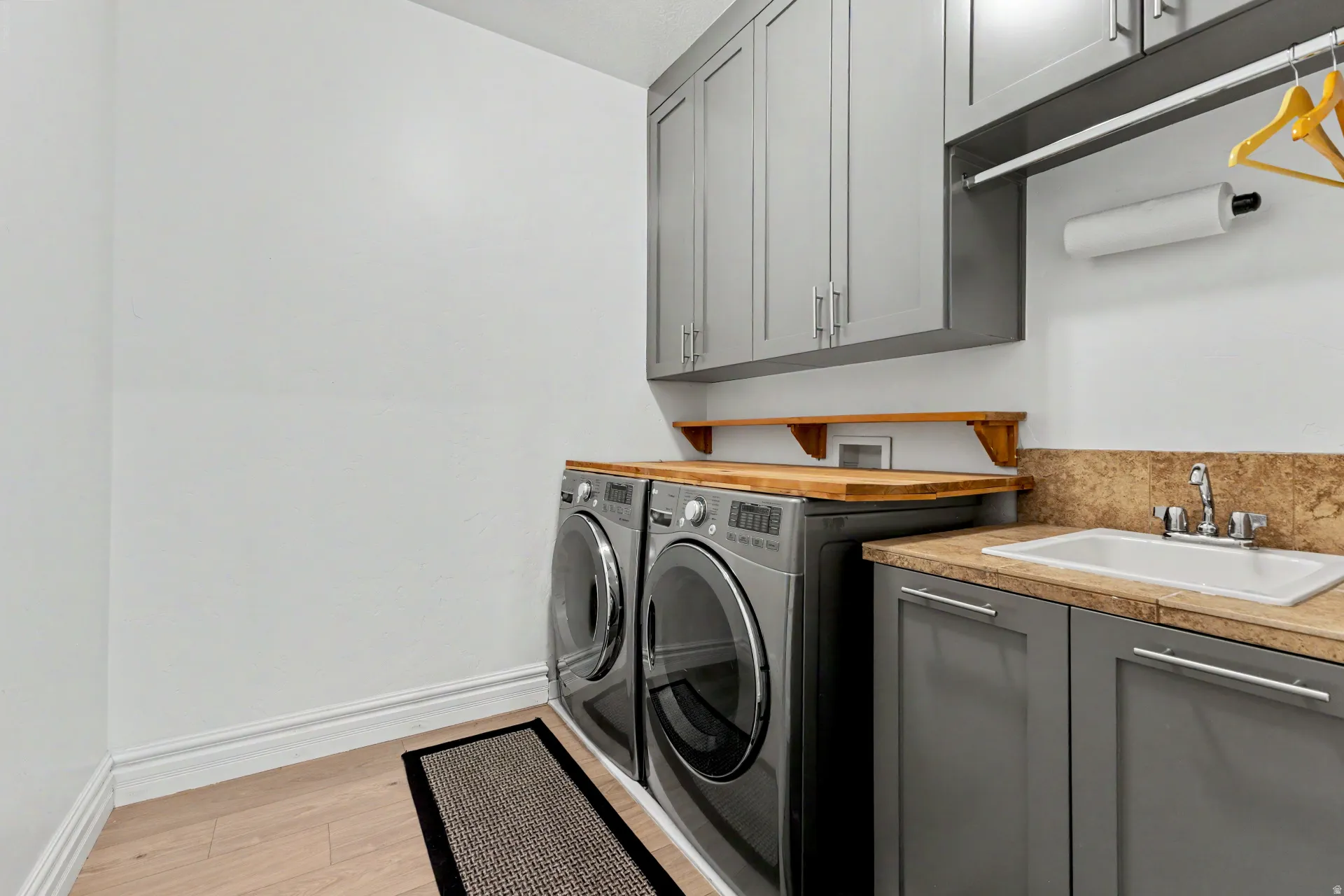 Laundry area featuring light wood finished floors, washer and dryer, and cabinet space