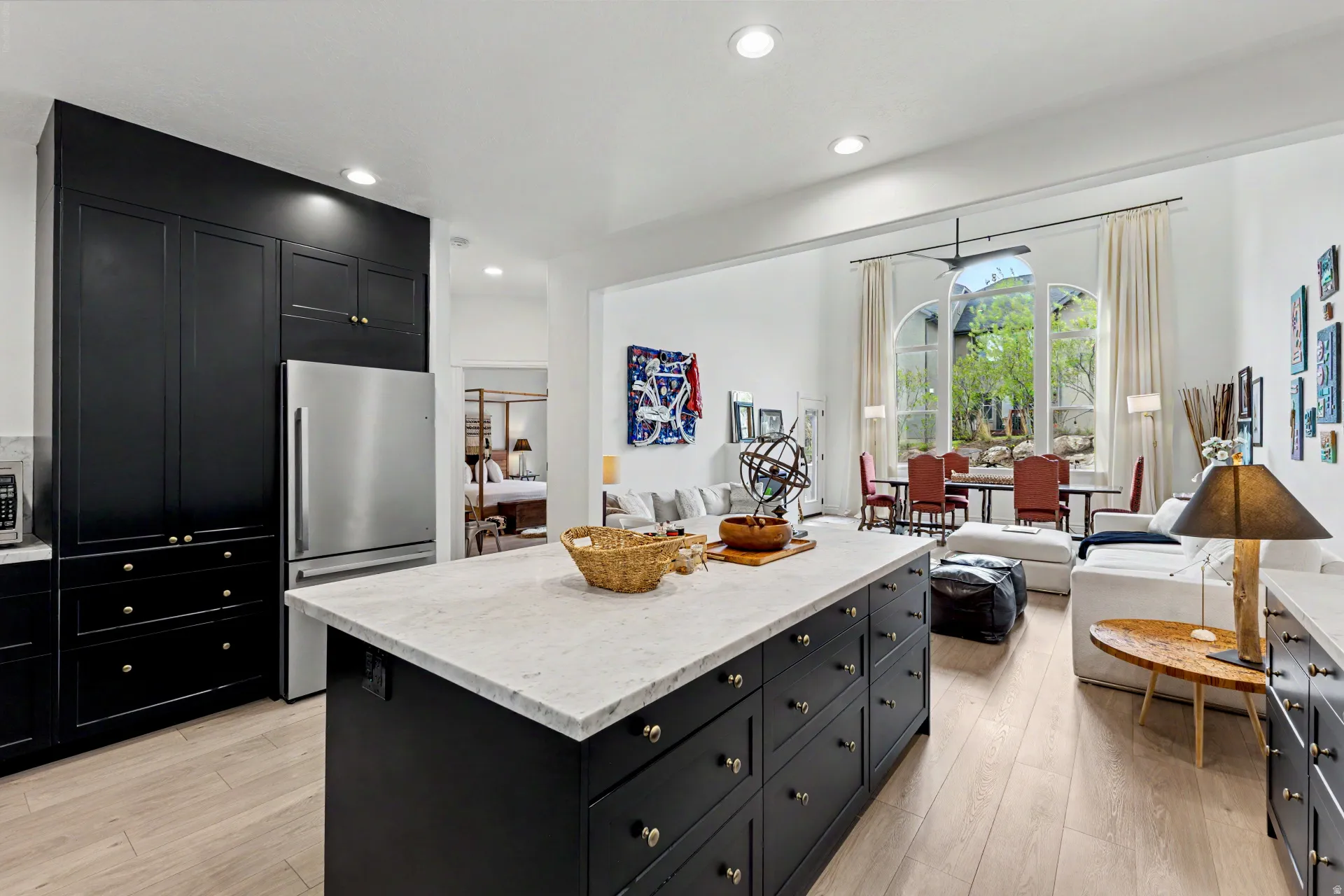Kitchen featuring dark cabinets, open floor plan, light stone counters, and recessed lighting