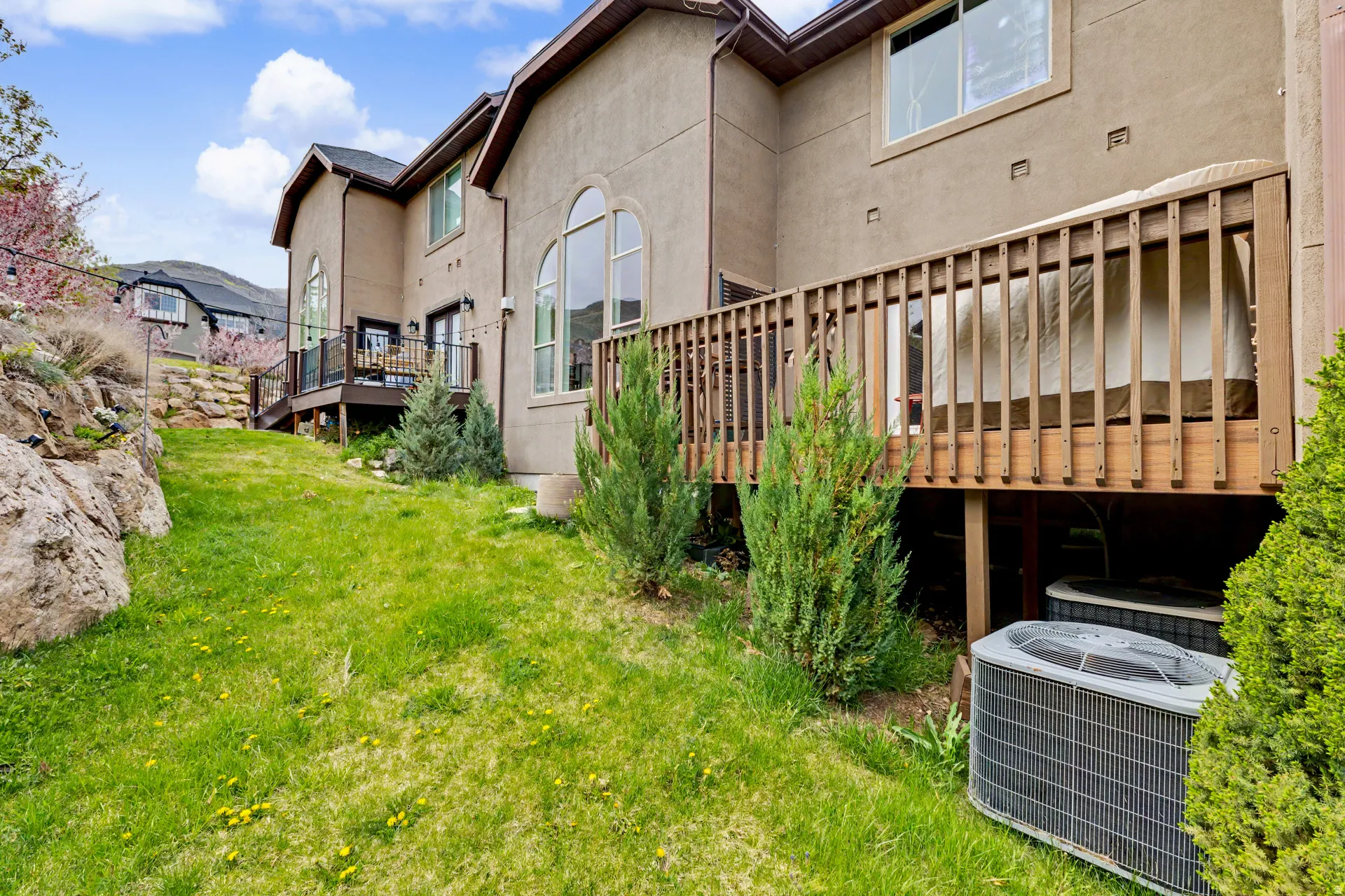 Rear view of house with a wooden deck, stucco siding, and a lawn