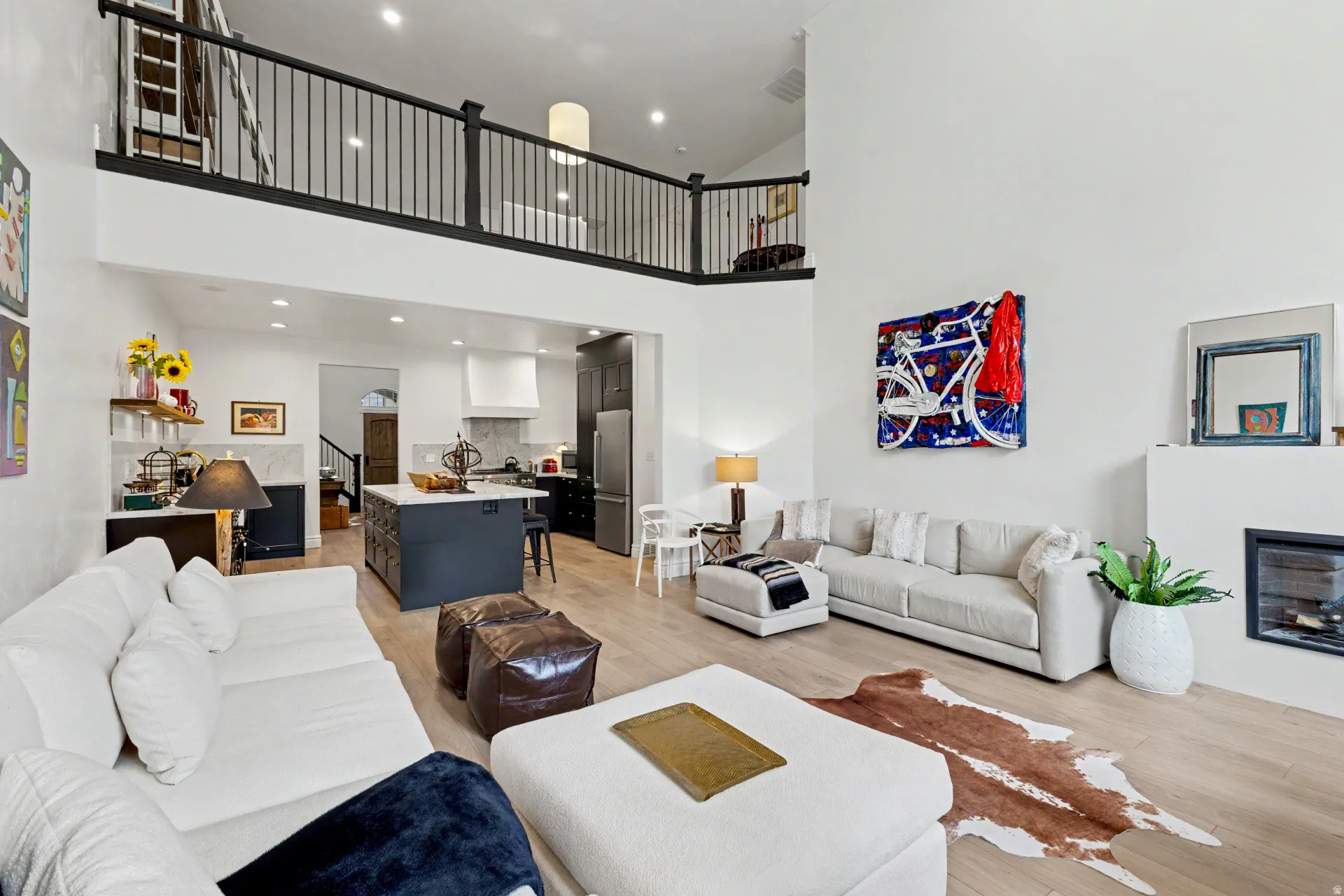 Living room featuring a glass covered fireplace, light wood-style flooring, recessed lighting, and a high ceiling