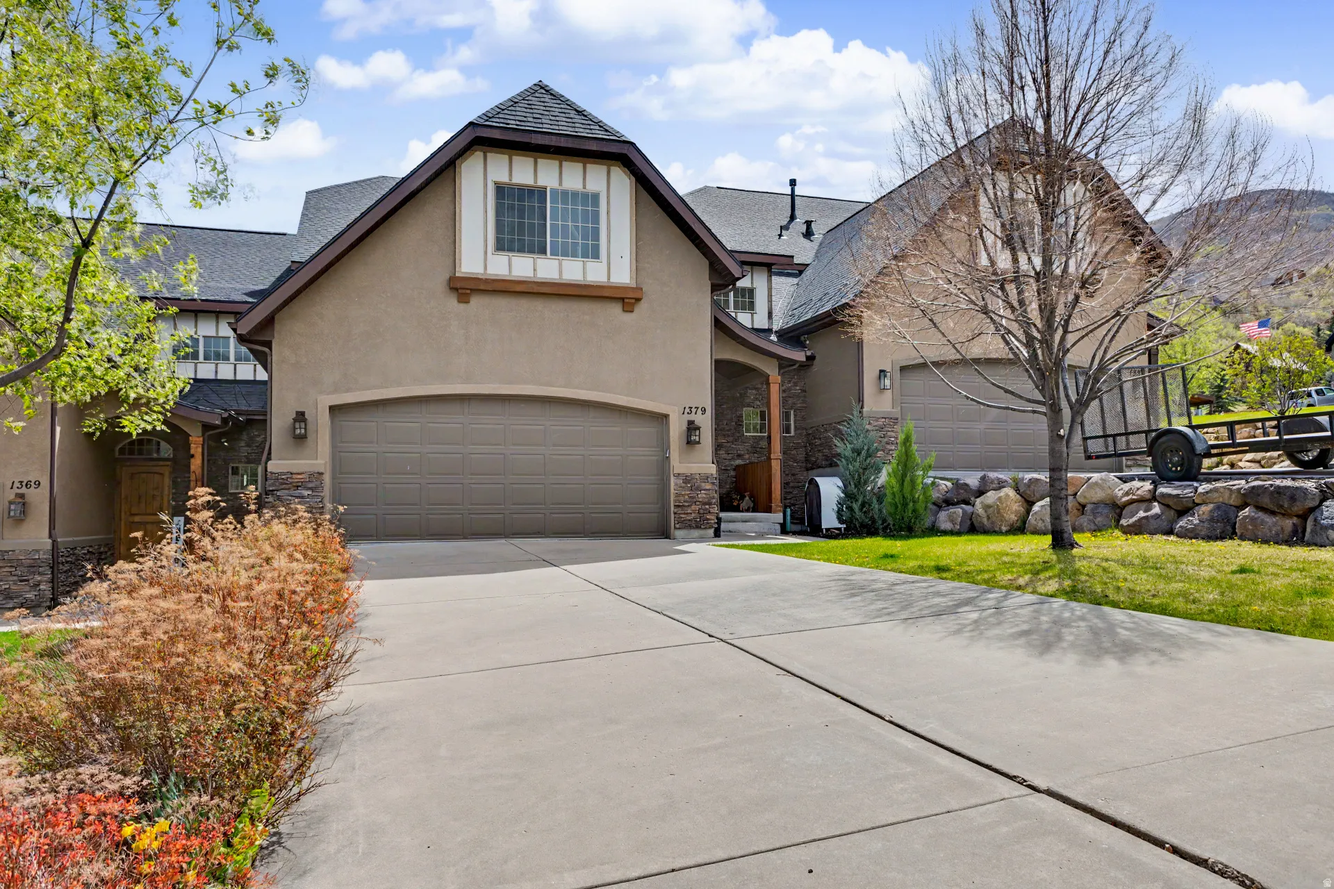 Traditional-style home featuring stone siding, concrete driveway, stucco siding, and an attached garage