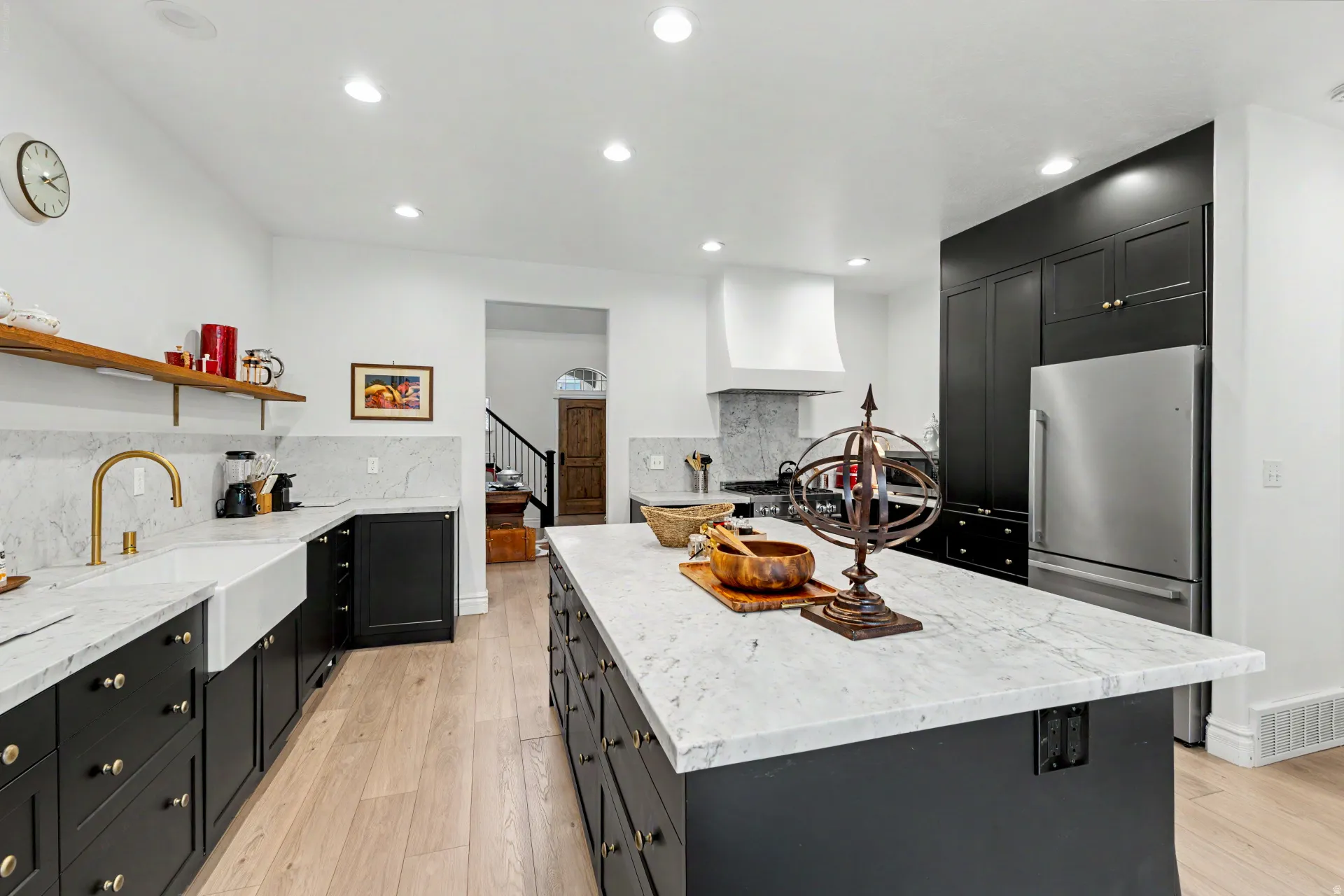 Kitchen featuring dark cabinetry, light stone countertops, decorative backsplash, a center island, and recessed lighting