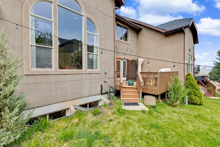 Rear view of house featuring a wooden deck, stucco siding, a yard, and a shingled roof