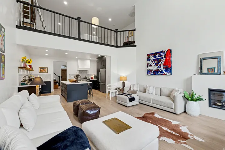 Living room featuring a glass covered fireplace, light wood-style flooring, recessed lighting, and a high ceiling