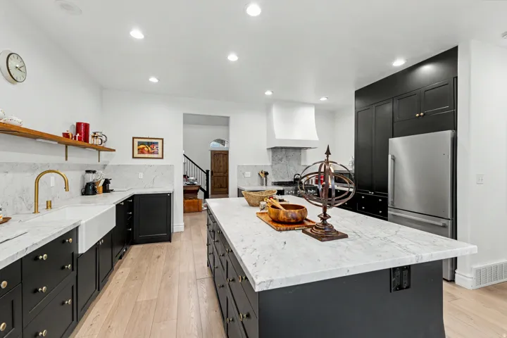 Kitchen featuring dark cabinetry, light stone countertops, decorative backsplash, a center island, and recessed lighting