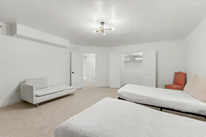 Bedroom with light colored carpet, a closet, a textured ceiling, and hanging lights