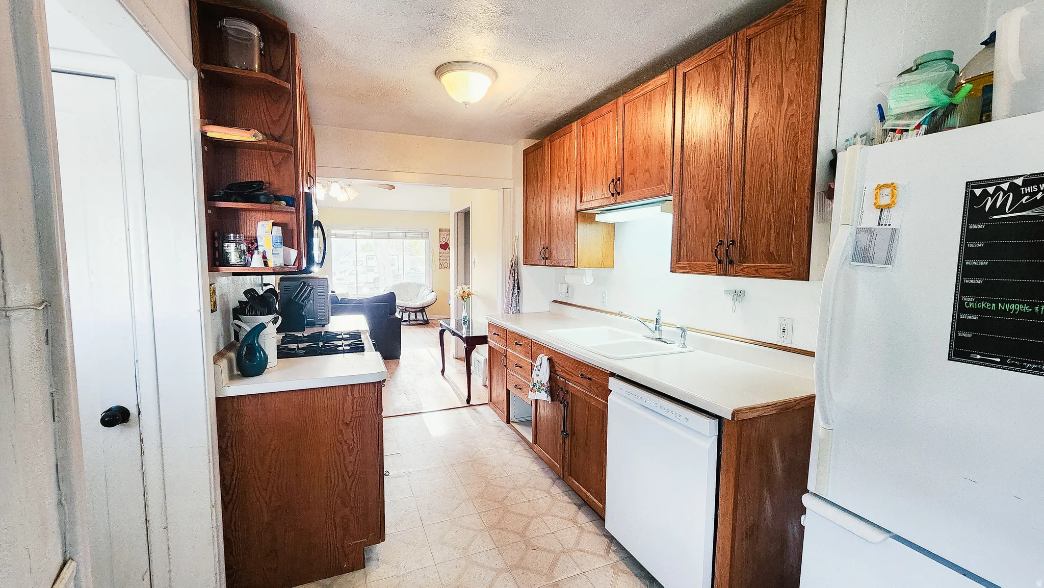 Kitchen featuring light floors, white appliances, open shelves, light countertops, and wood finish cabinetry