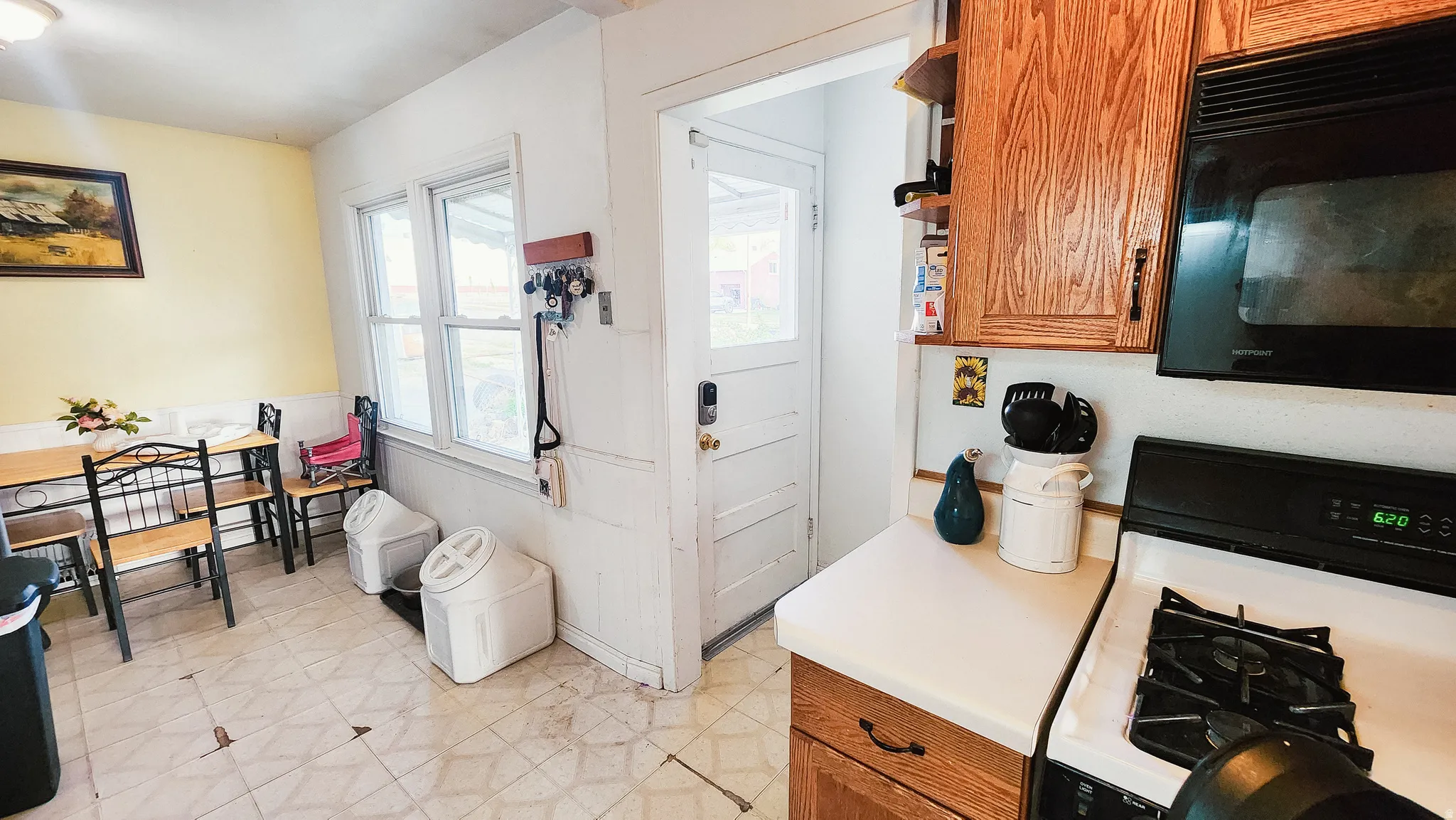 Kitchen with gas stove, black microwave, light flooring, light countertops, and wood finish cabinetry