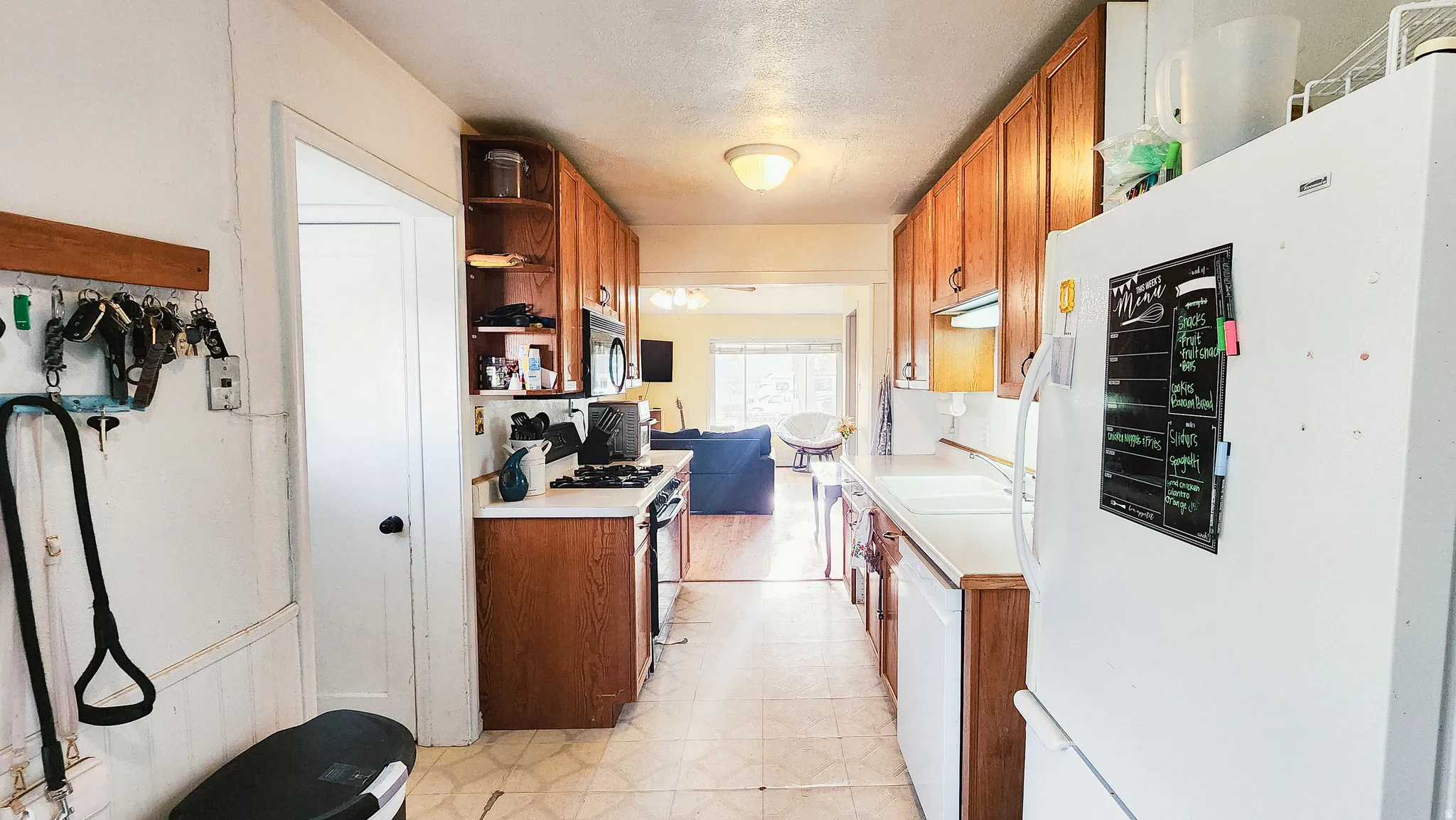Kitchen featuring white appliances, light countertops, light floors, open shelves, and wood finish cabinets