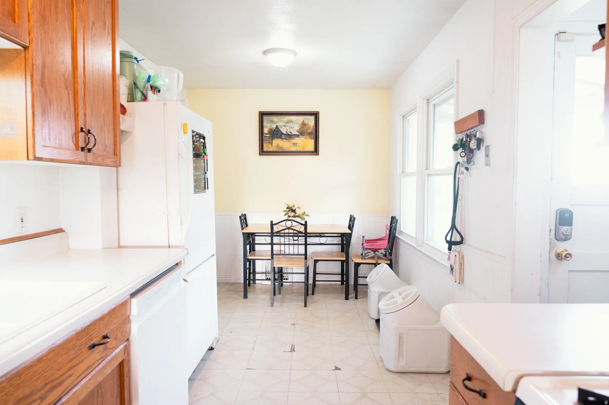 Kitchen with light flooring, light countertops, wood finish cabinets, white appliances, and wainscoting