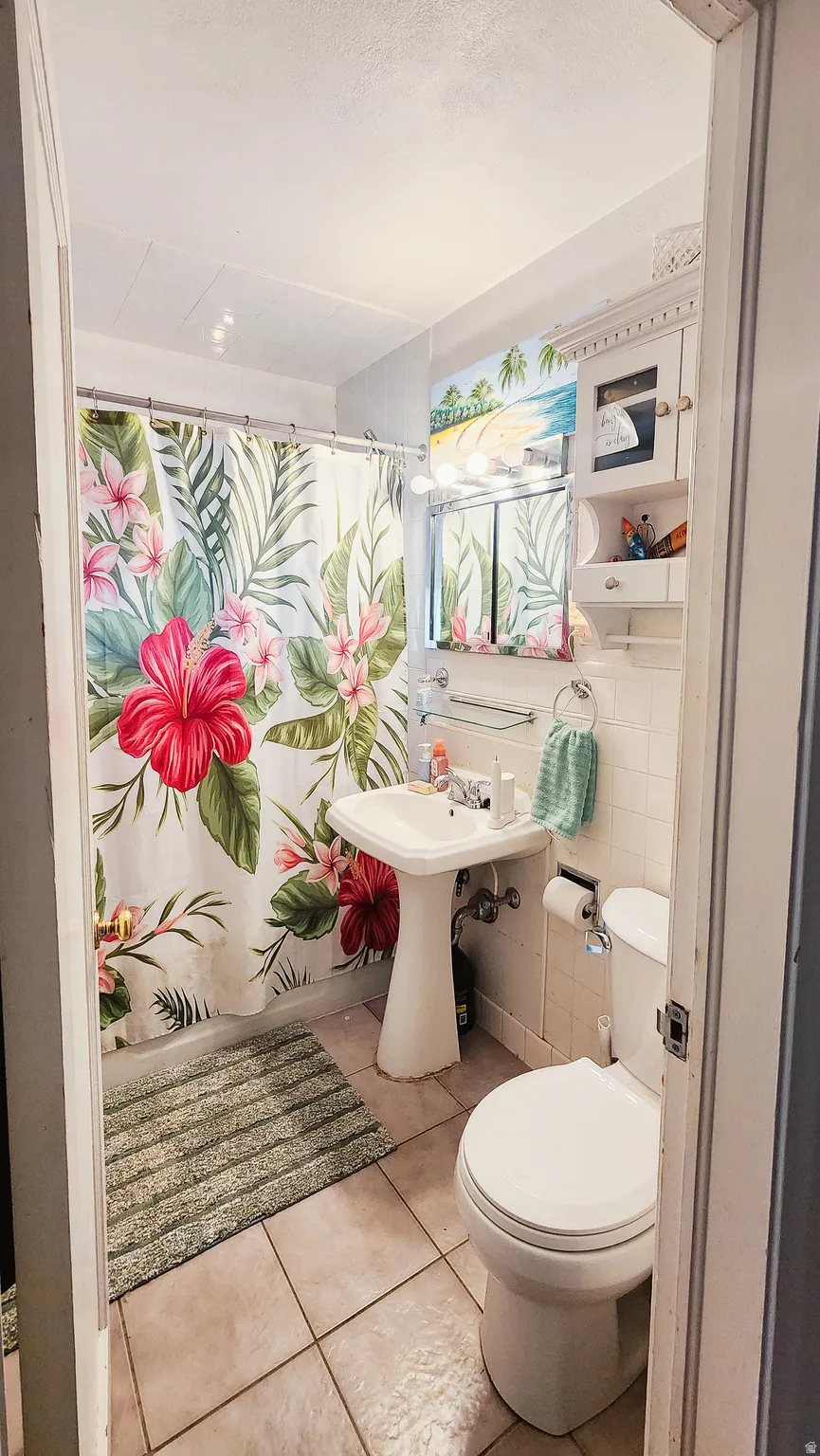 Full bath with tile walls, light tile patterned flooring, and shower / tub combo