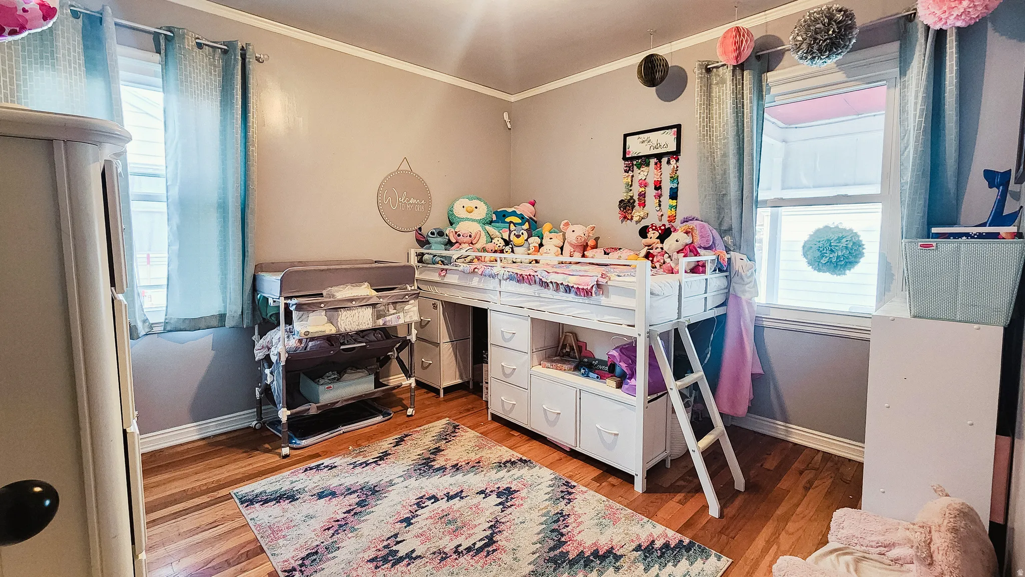 Bedroom with light wood-style floors, multiple windows, and crown molding