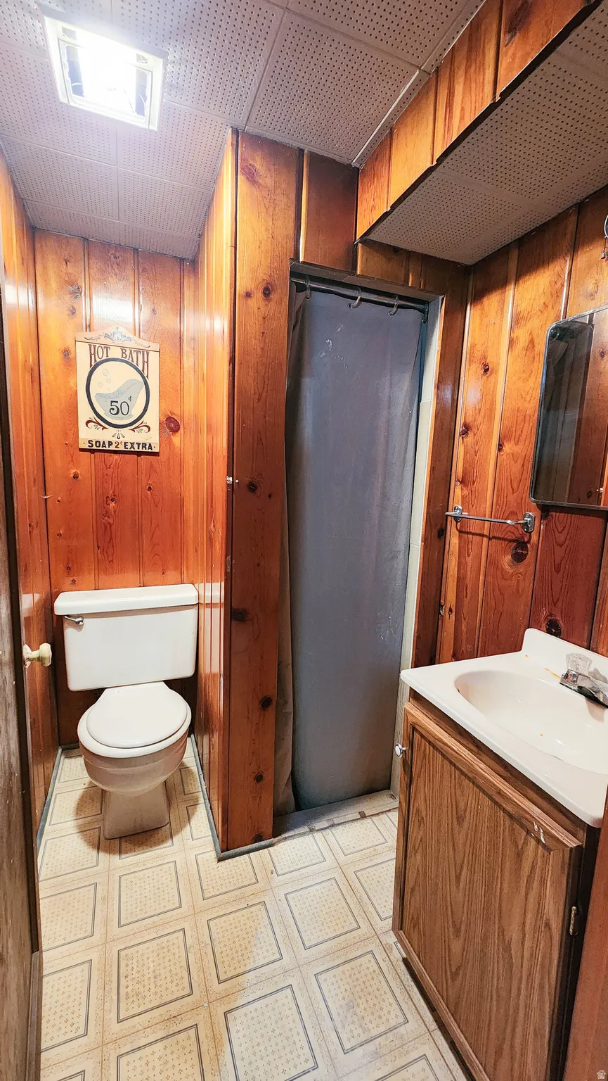 Bathroom featuring wood walls, a stall shower, and vanity