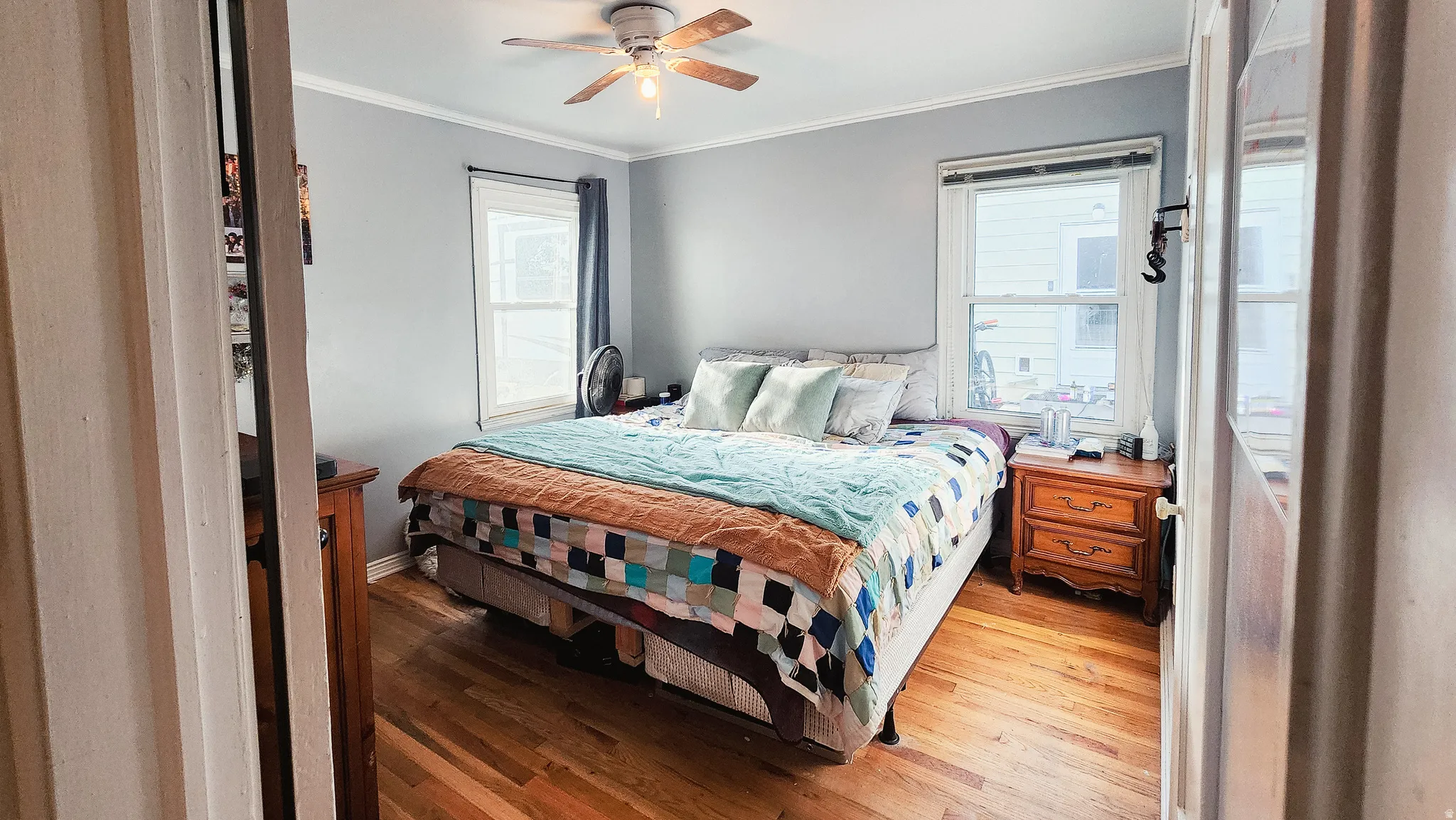 Bedroom with hardwood / wood-style floors, ceiling fan, and crown molding
