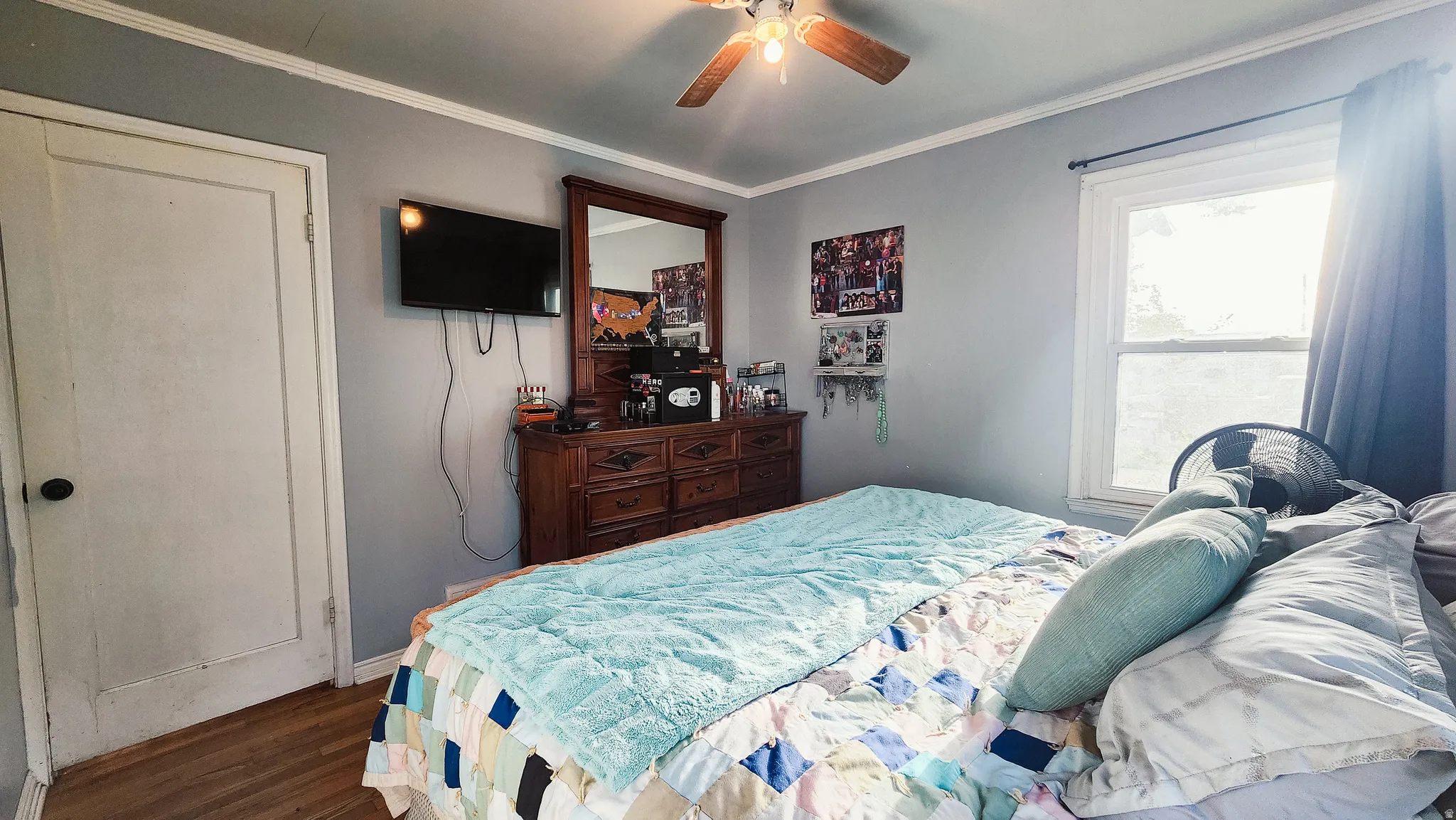 Bedroom with dark wood-type flooring, a ceiling fan, and ornamental molding