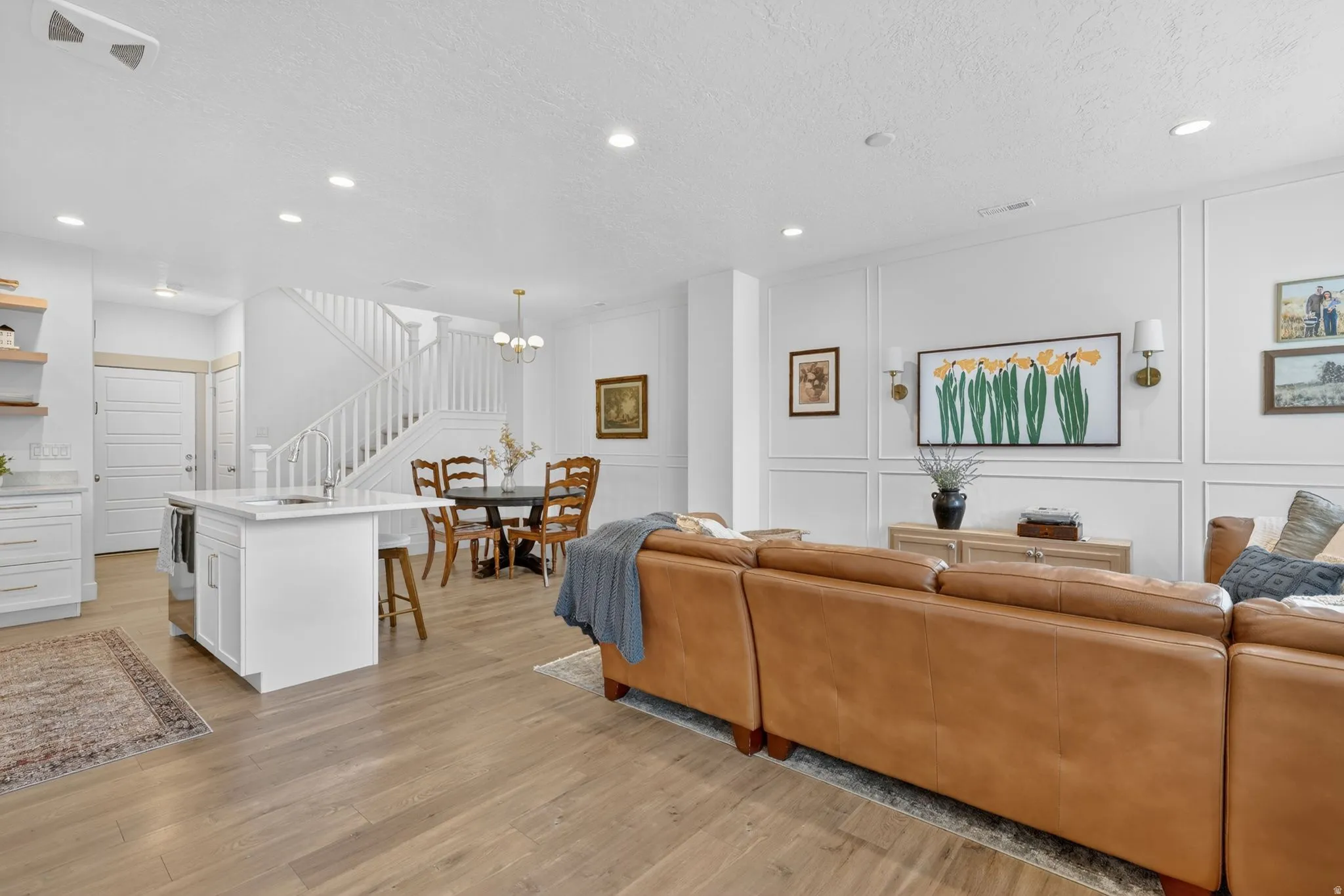 Living room featuring a decorative wall, light wood-style flooring, a textured ceiling, and suspended lighting