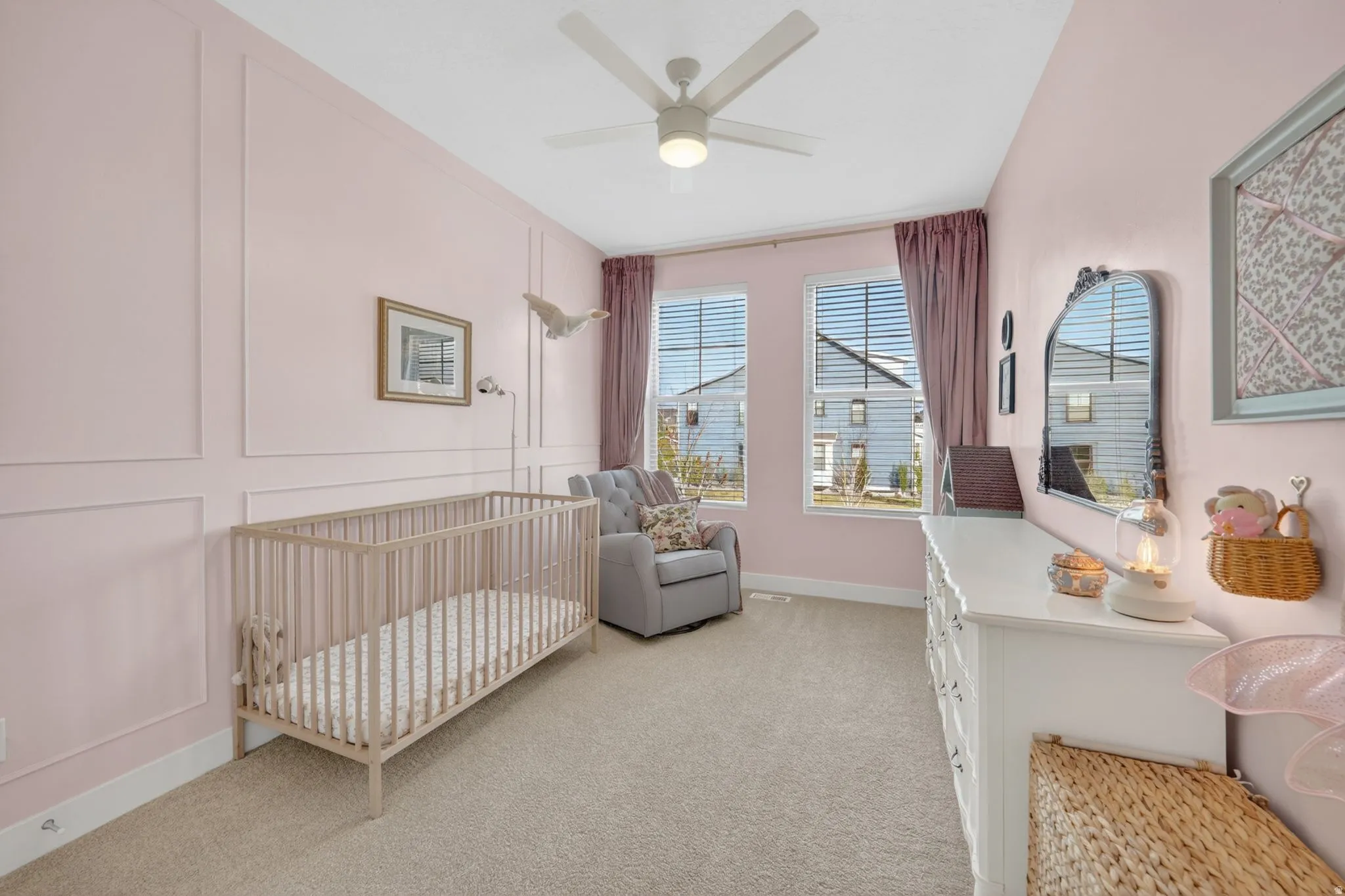 Bedroom featuring a decorative wall, a nursery area, light carpet, and ceiling fan