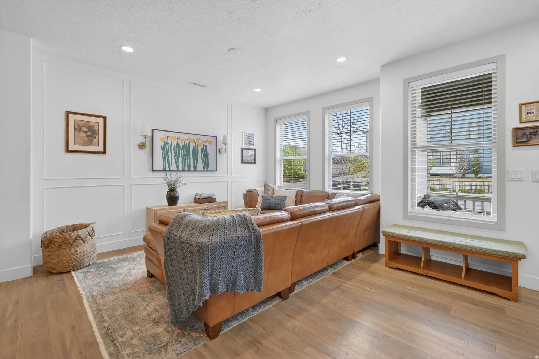 Living room featuring a decorative wall, light wood-type flooring, a textured ceiling, and recessed lighting