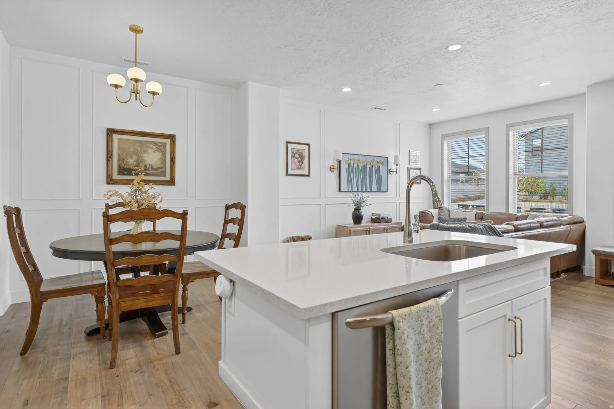 Kitchen with a decorative wall, white cabinets, light wood finished floors, dishwasher, and light stone counters