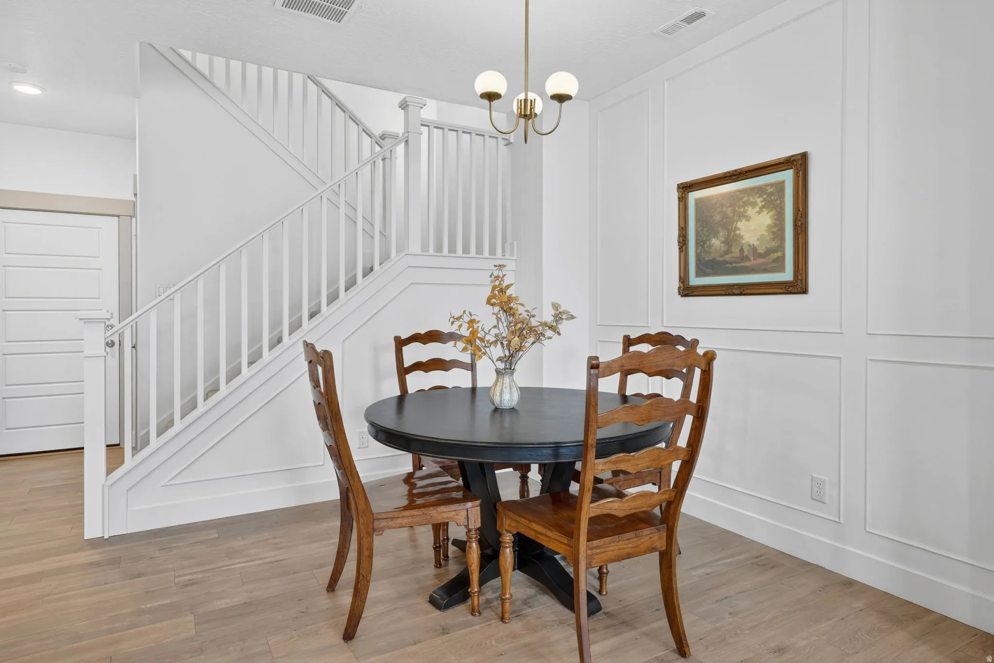 Dining area featuring a decorative wall, hanging lights, and light wood-style floors