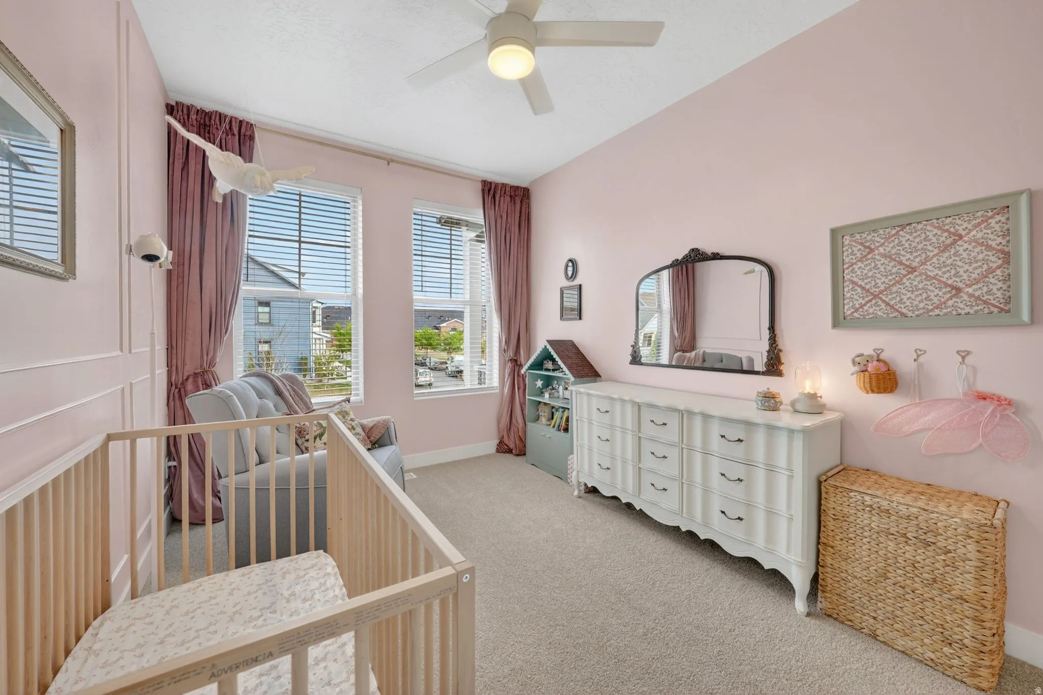 Bedroom featuring light carpet, a ceiling fan, and a crib