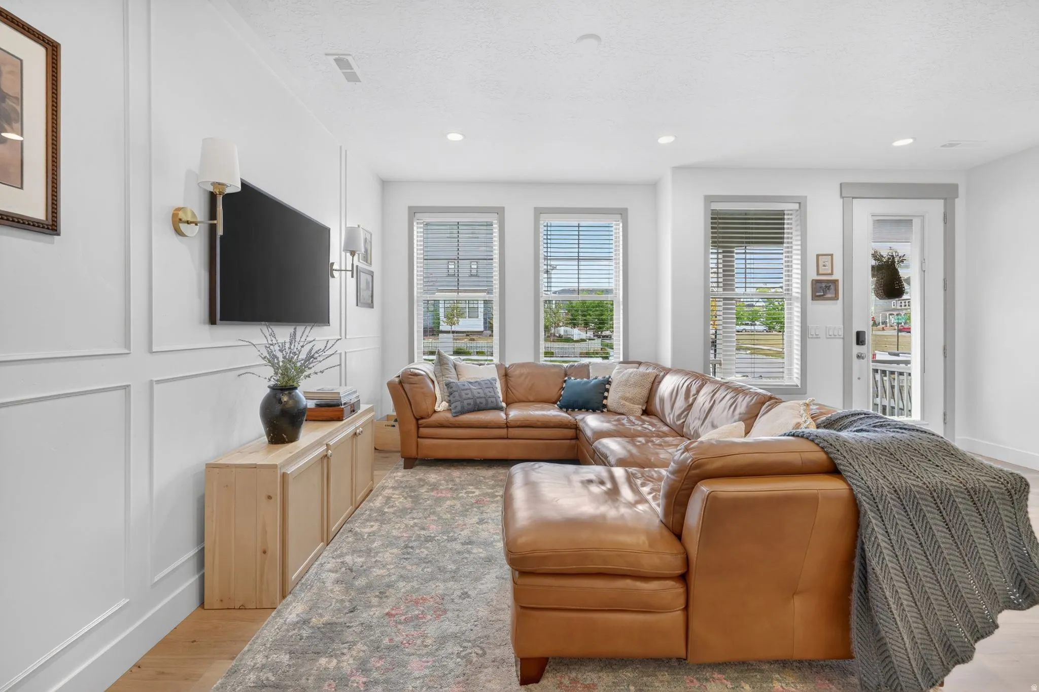 Living room featuring light wood-style floors, a decorative wall, and recessed lighting