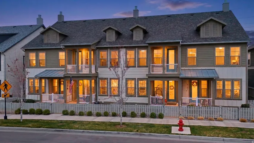 Rear view of house featuring a chimney, a fenced front yard, and a balcony