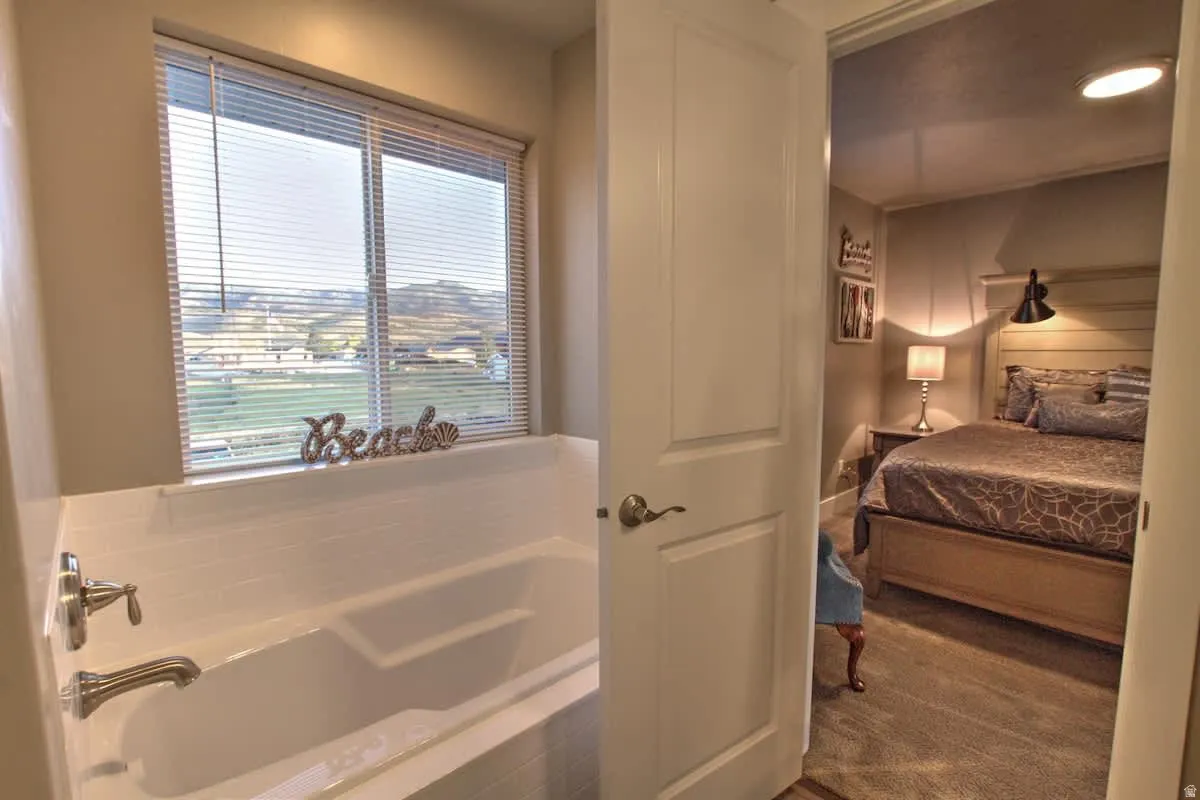 Ensuite bathroom featuring a garden tub and dark colored carpet