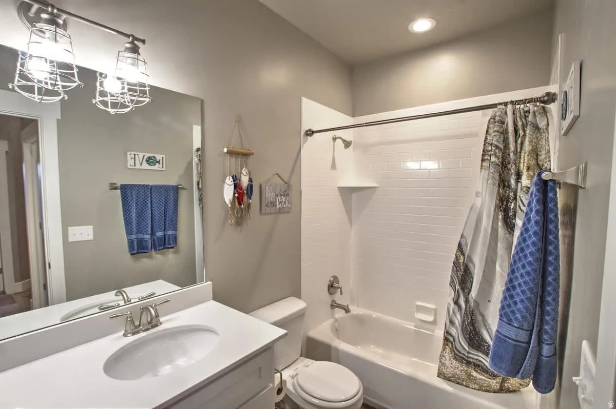 Bathroom with vanity, shower / bathtub combination with curtain, and a chandelier