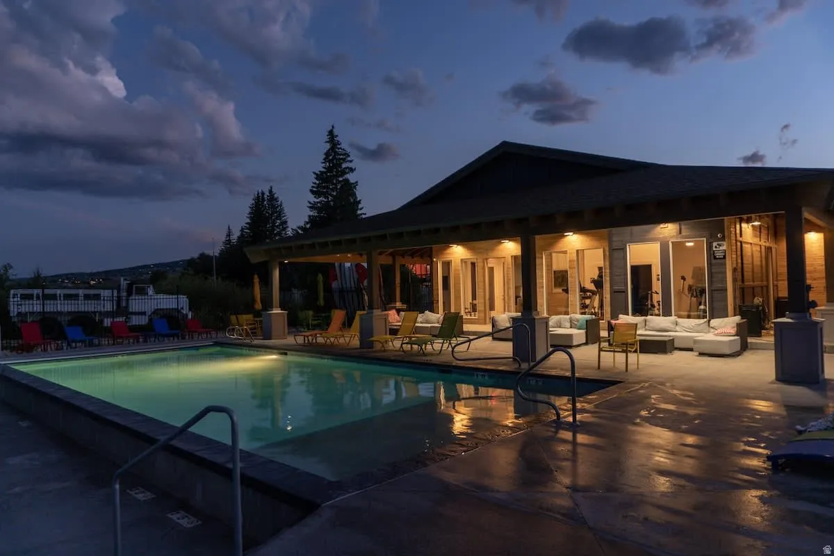Pool at dusk featuring a community pool, a patio area, and an outdoor living space