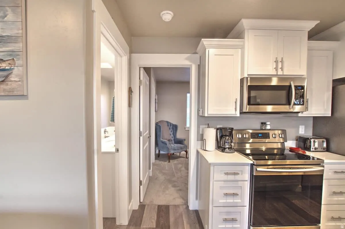 Kitchen featuring stainless steel appliances, white cabinets, and dark wood-style flooring