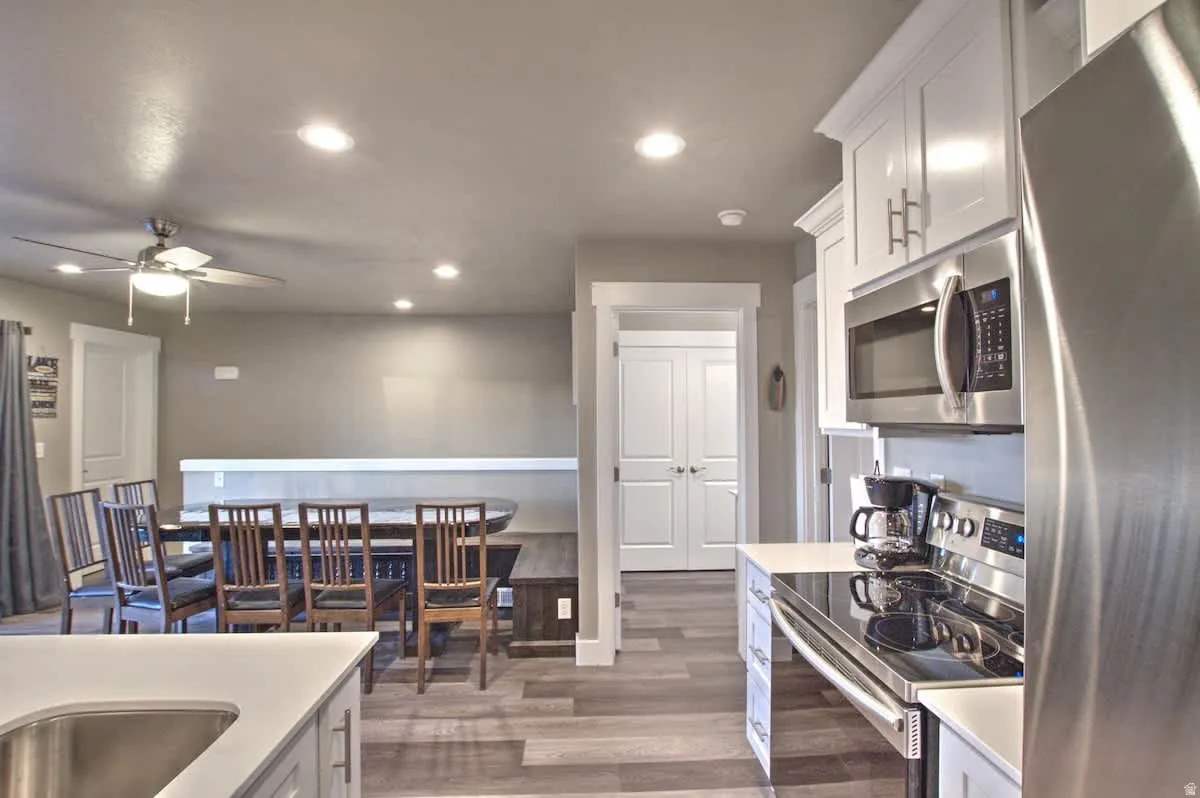 Kitchen with stainless steel appliances, white cabinetry, recessed lighting, dark wood-style floors, and ceiling fan