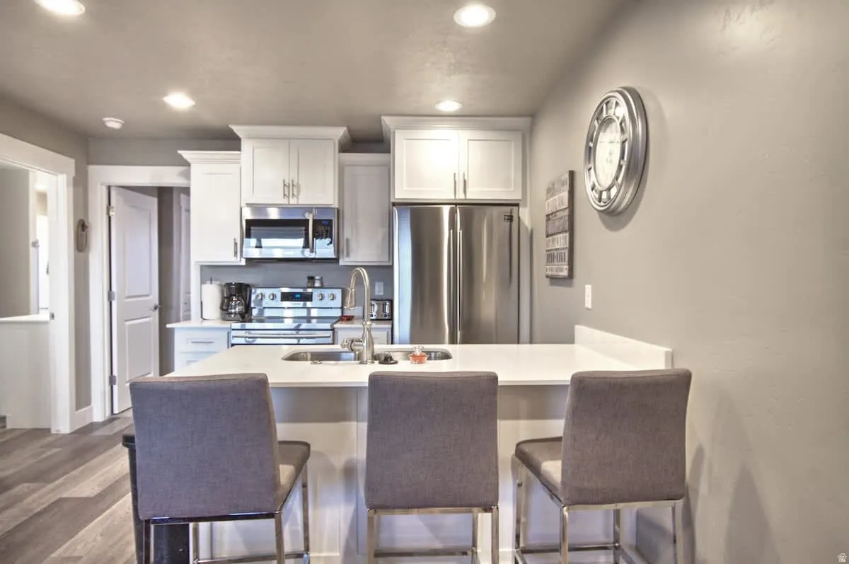 Kitchen featuring stainless steel appliances, a peninsula, a breakfast bar, white cabinets, and recessed lighting