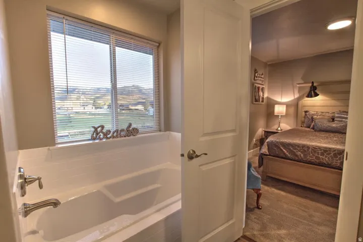 Ensuite bathroom featuring a garden tub and dark colored carpet