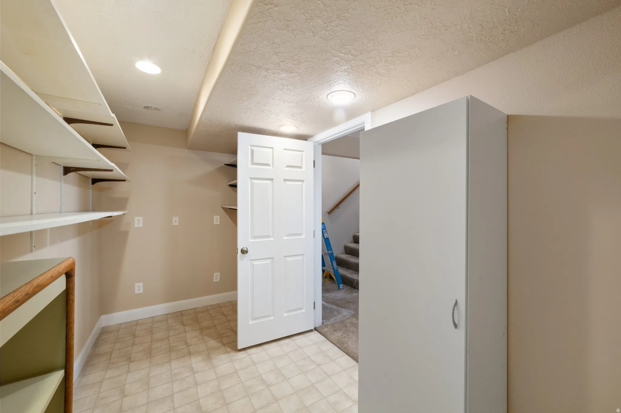 Finished below grade area featuring a textured ceiling, light floors, and recessed lighting