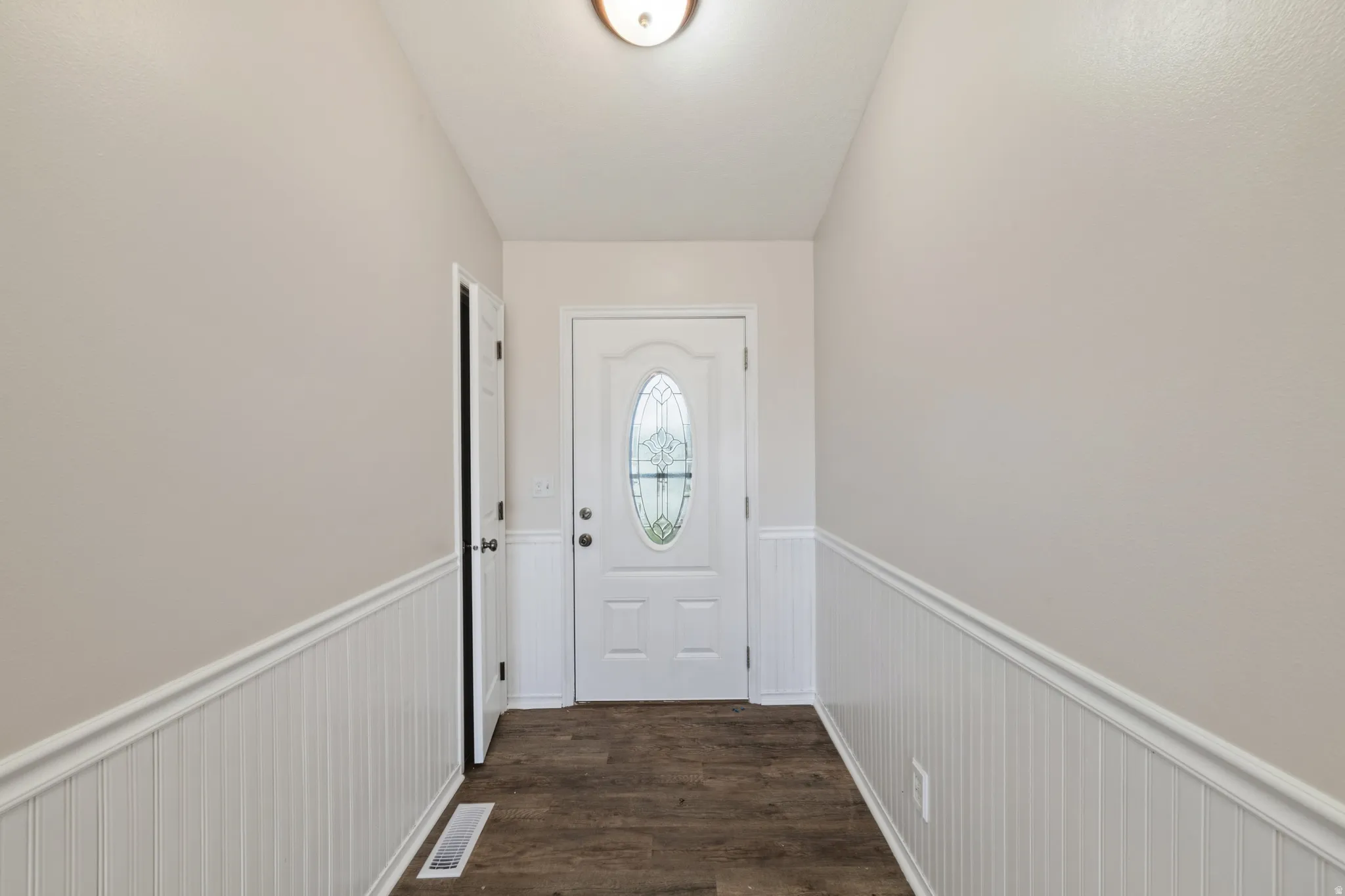 Doorway to outside with wainscoting and wood finished floors