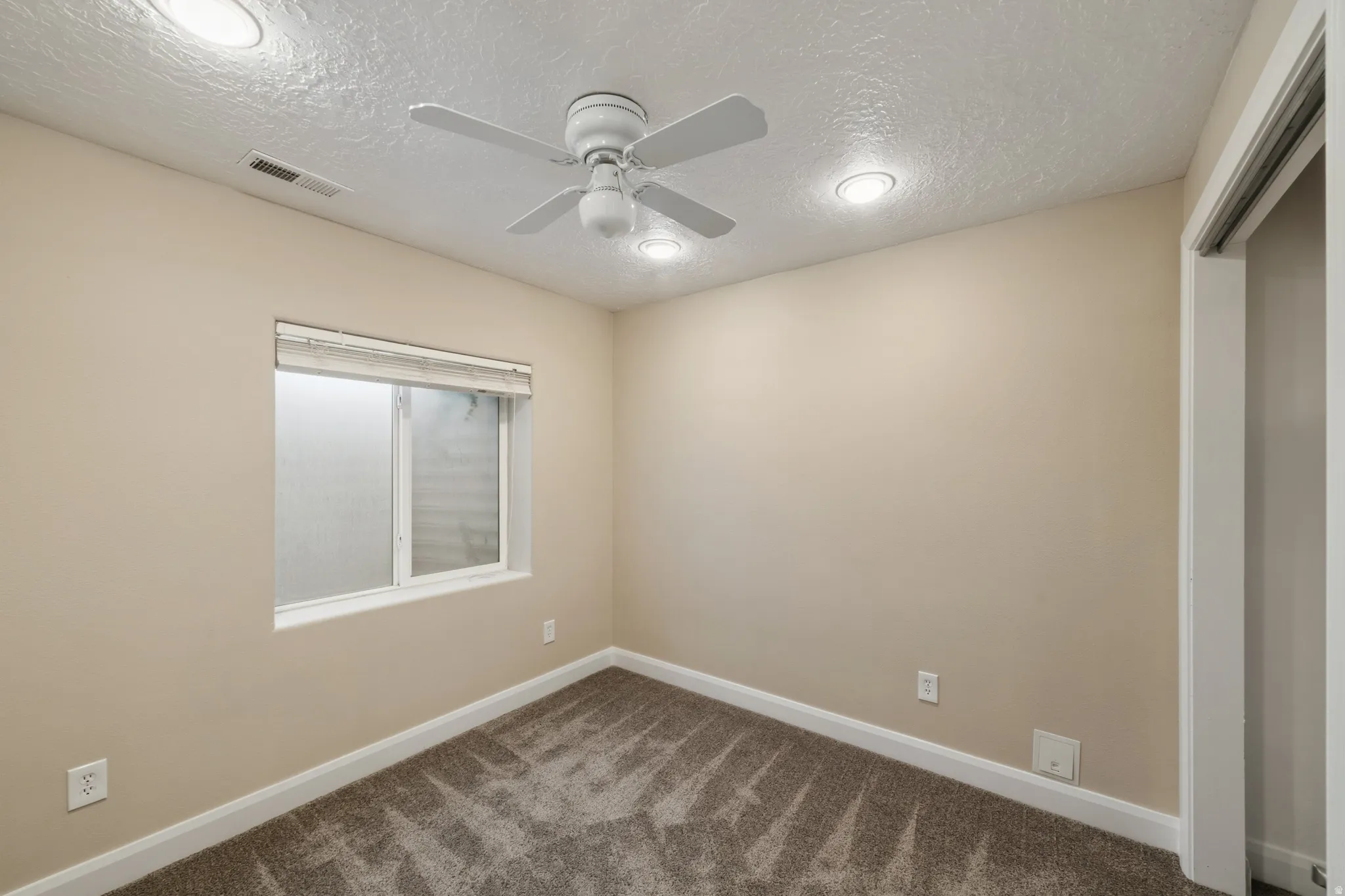 Spare room with a textured ceiling, a ceiling fan, and dark carpet