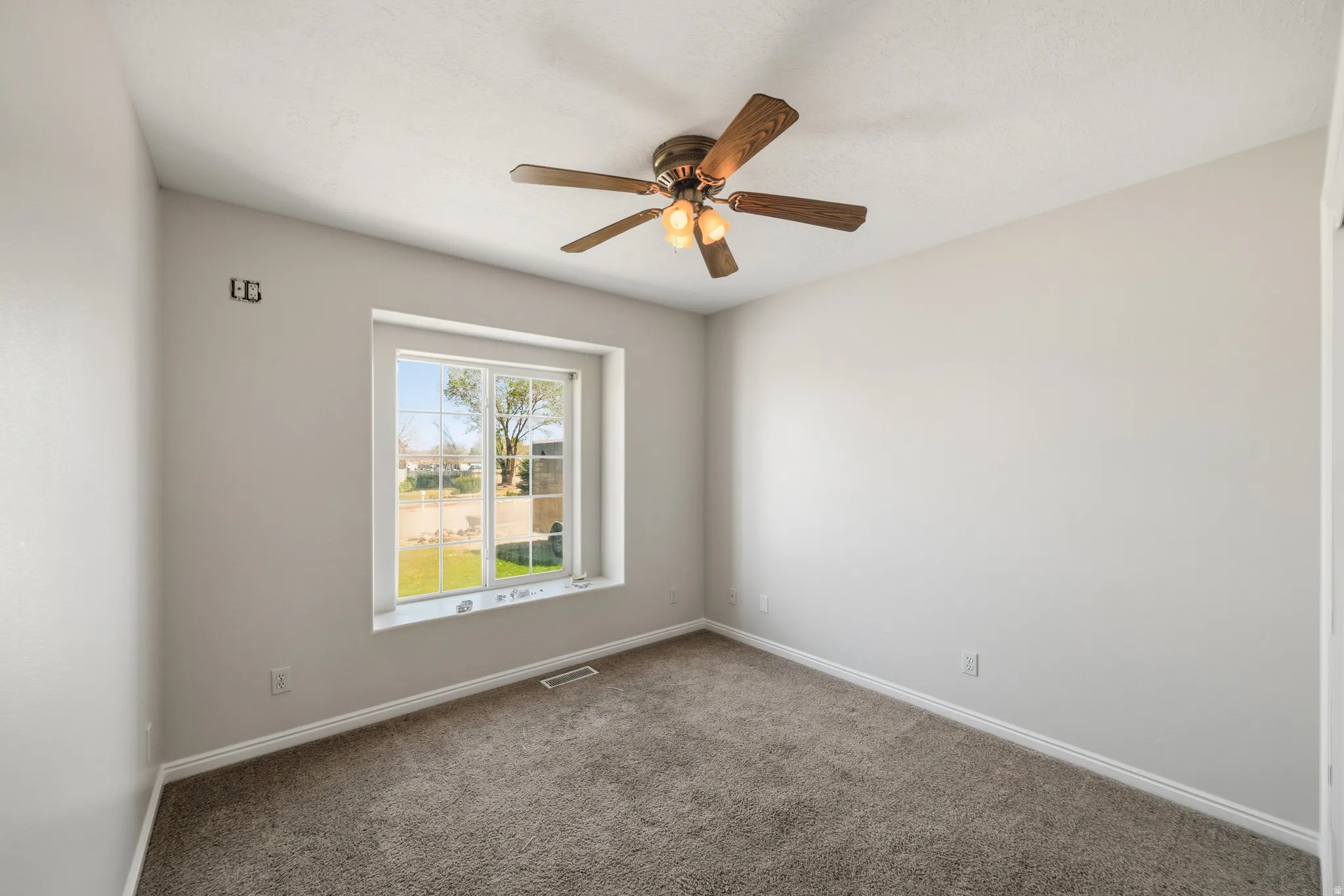 Spare room with dark colored carpet and a ceiling fan