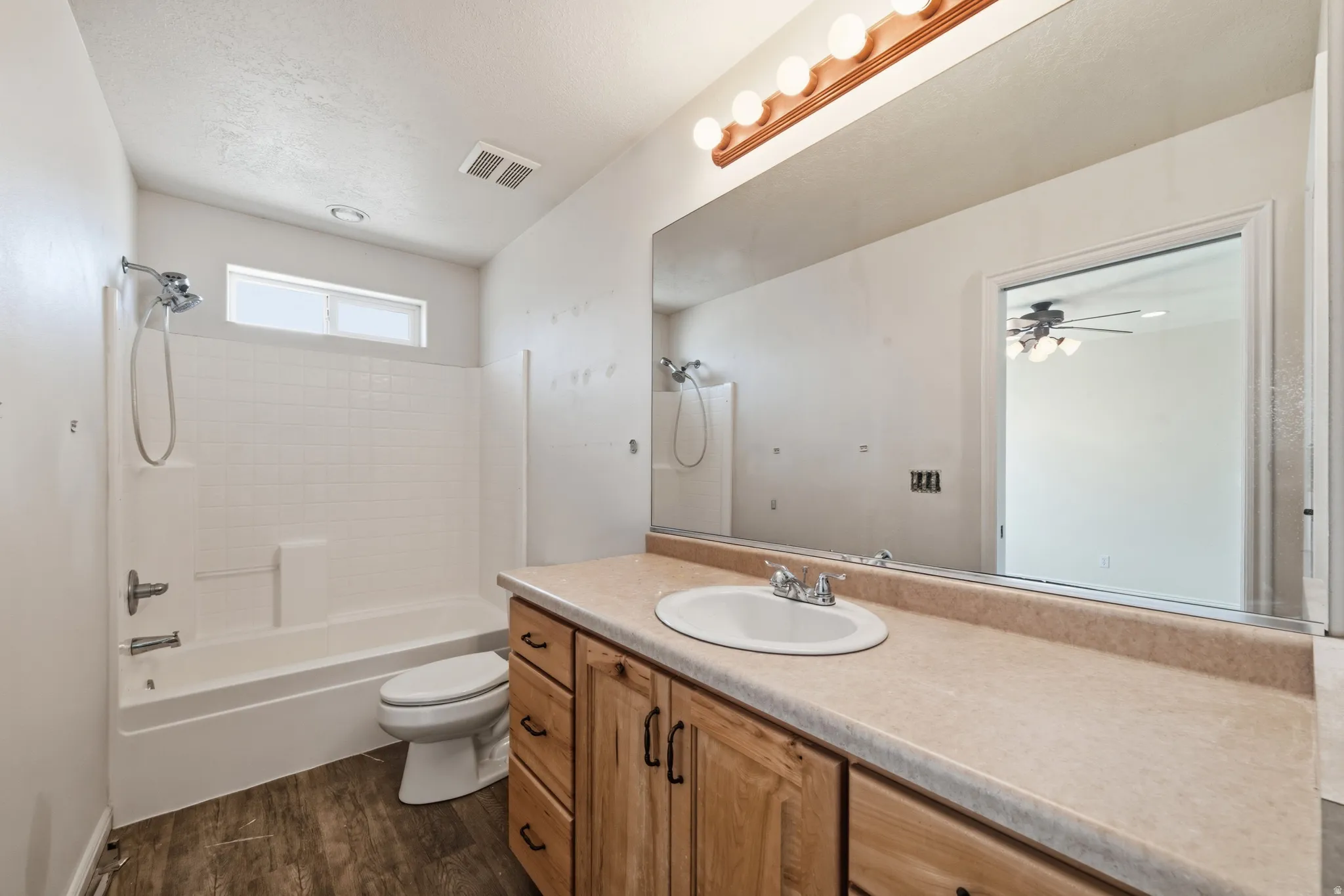 Full bath with vanity, shower / tub combination, dark wood finished floors, and ceiling fan