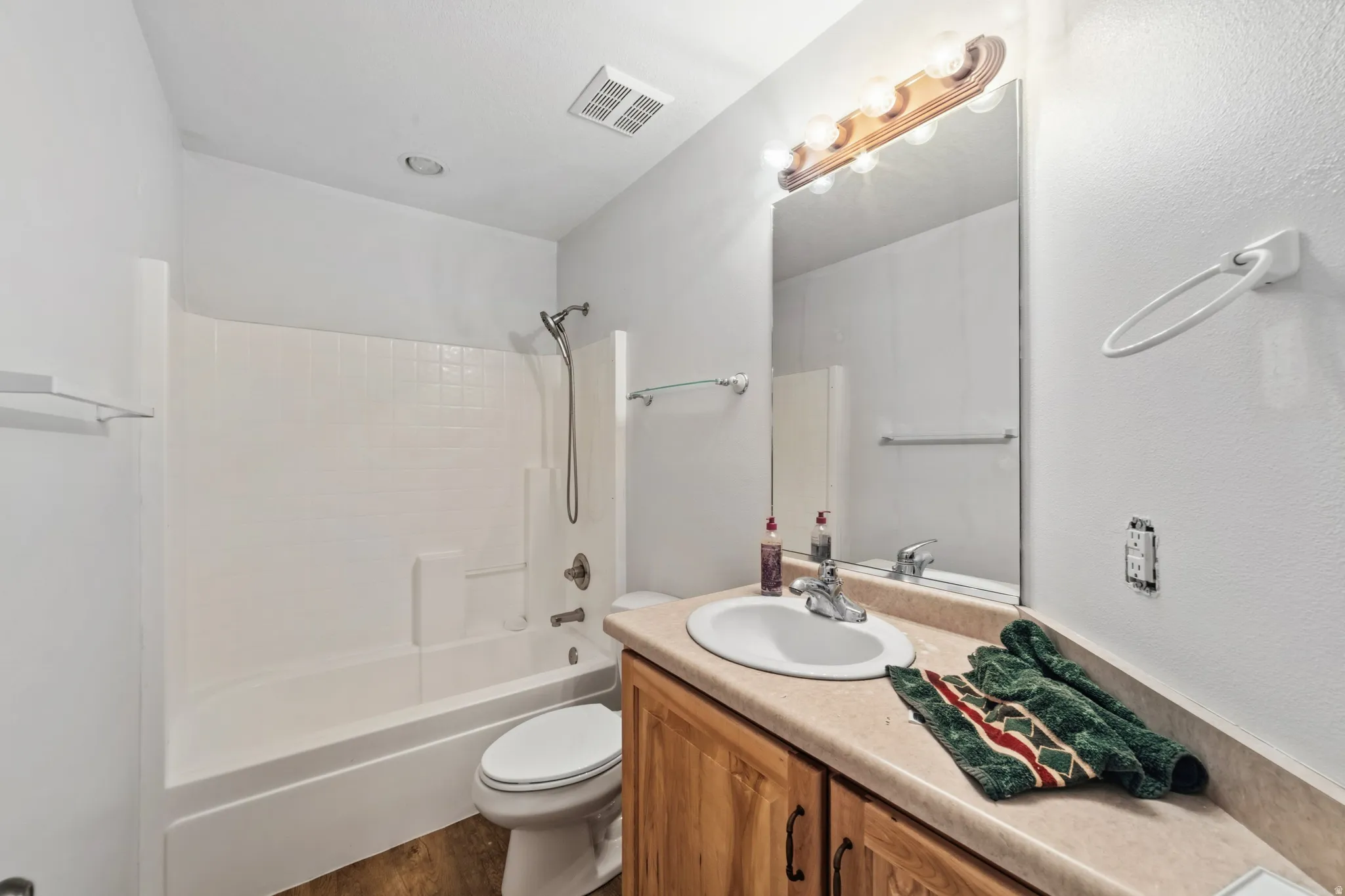 Bathroom with vanity, shower / bath combination, and dark wood-style flooring