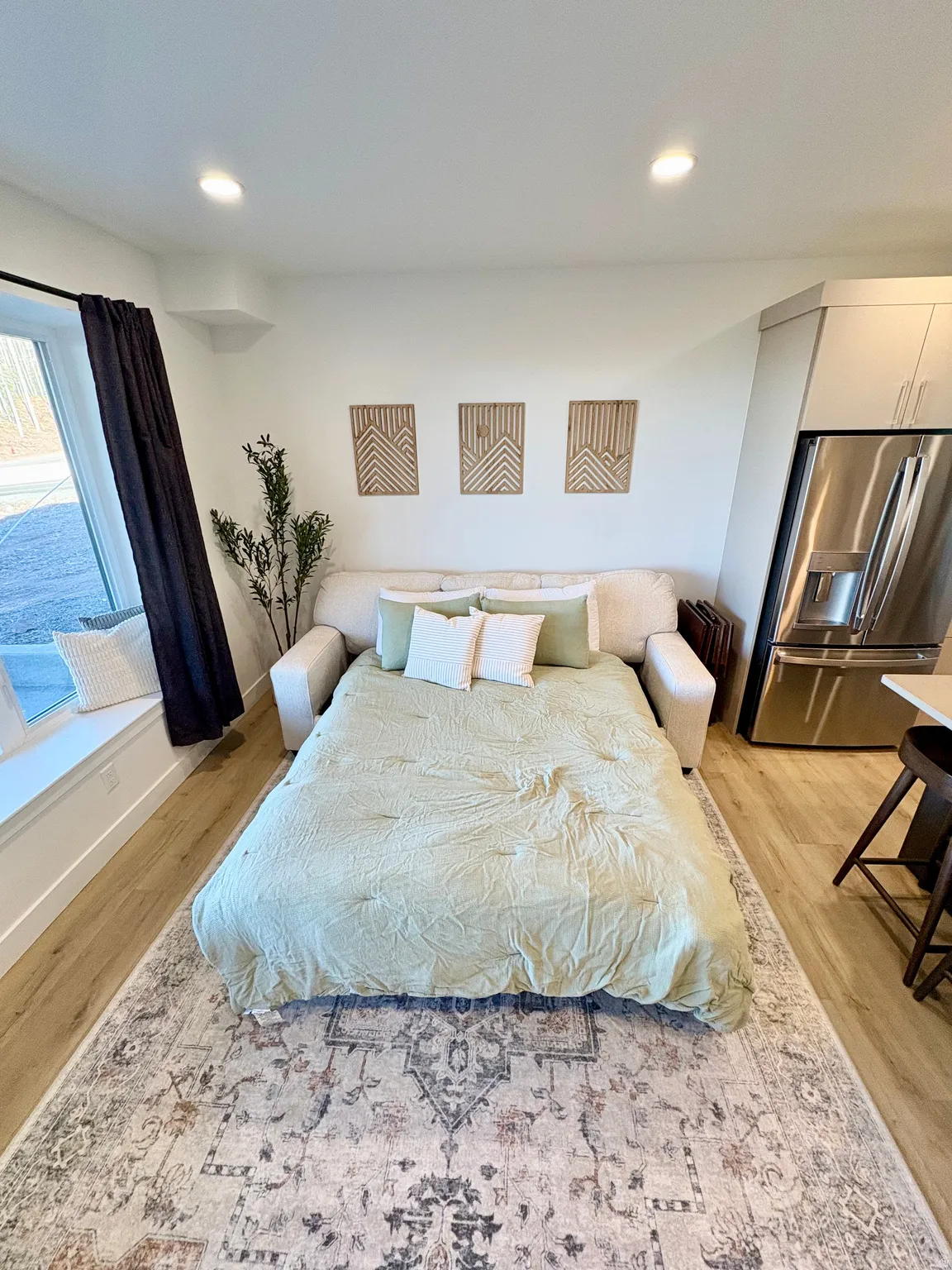 Bedroom featuring stainless steel refrigerator with ice dispenser, light wood-style floors, and recessed lighting