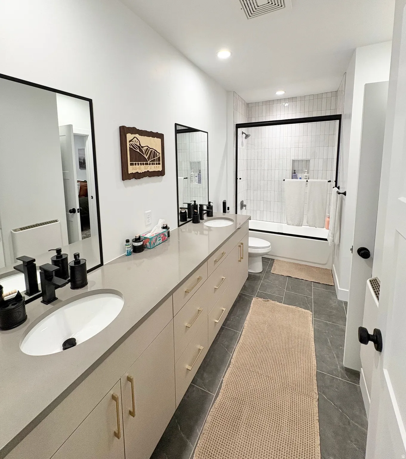 Full bathroom with double vanity, enclosed tub / shower combo, recessed lighting, and dark tile patterned flooring