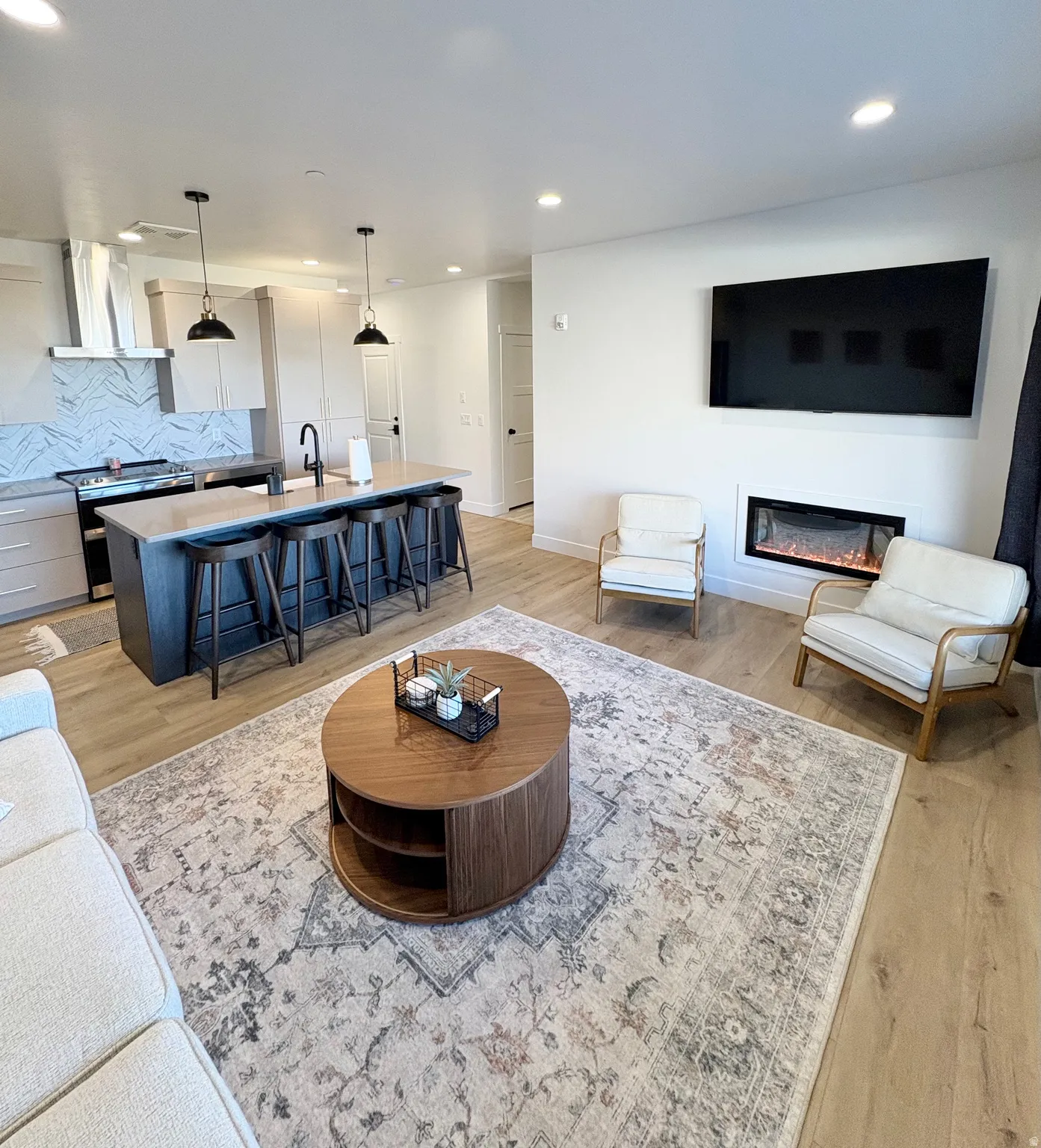 Living area with light wood-style floors, a glass covered fireplace, and recessed lighting