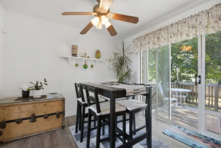 Wood-finish flooring, ceiling fan with integrated lighting, and a sliding glass door providing direct access to an outdoor deck