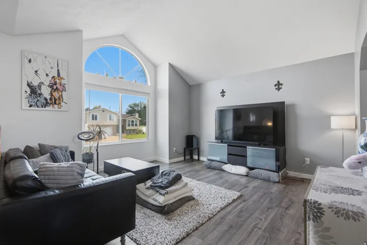 Vaulted ceiling with an arched transom window, wood-finish flooring, and light gray wall color