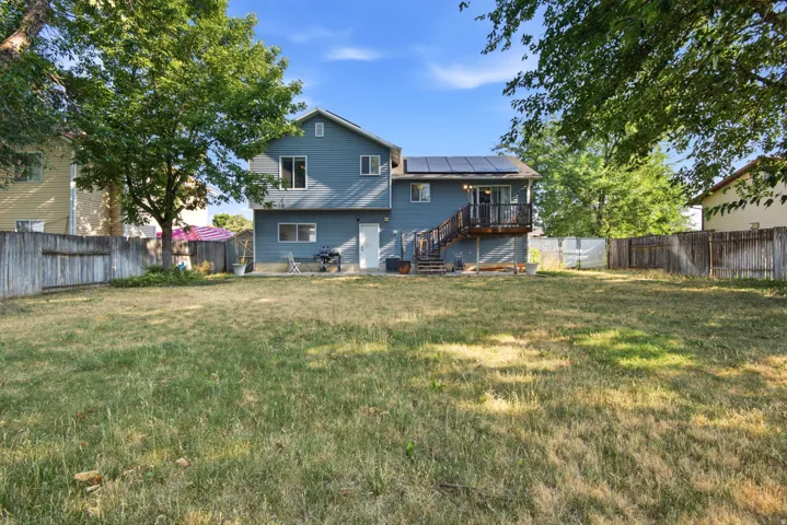 Expansive backyard with a wood privacy fence, multi-level deck, and solar panels