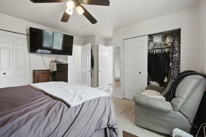 Ceiling fan with integrated lighting, multiple white bi-fold closet doors, and light-colored flooring
